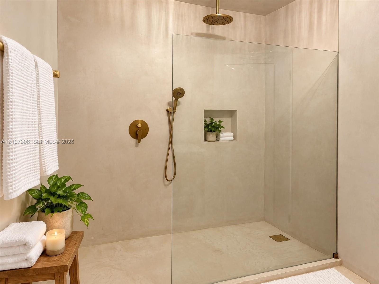 Walk-in shower featuring a seamless glass enclosure, monochromatic wall finish, brass-tone rain showerhead, matching hand-held sprayer, and a built-in
