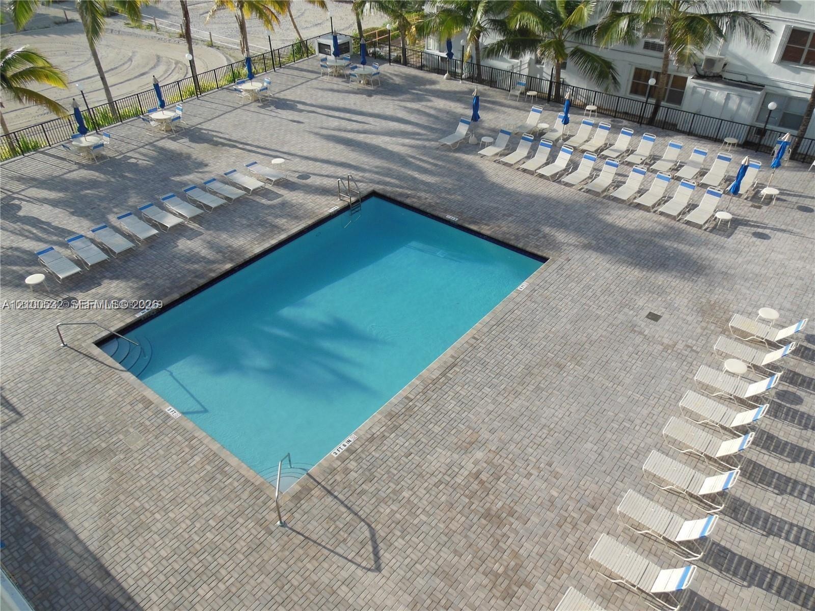 Rectangular swimming pool featuring stone paver decking, metal perimeter fencing, and integrated pool stairs