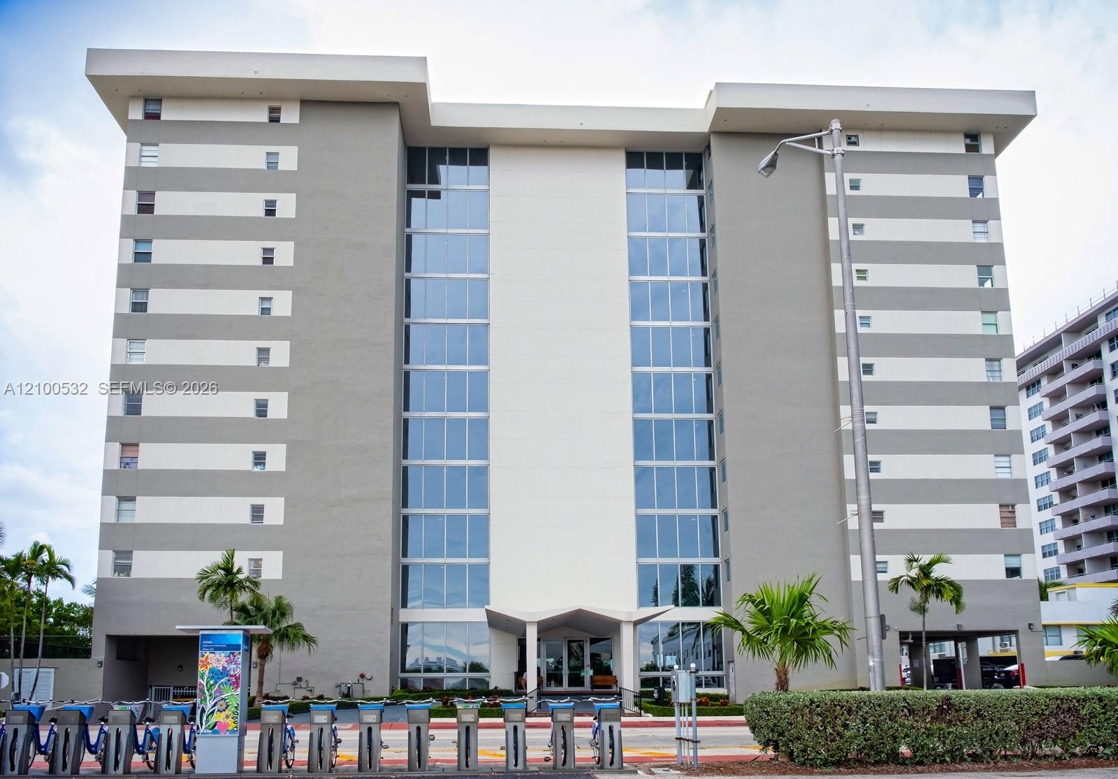 Multi-story mid-century modern architectural design featuring a central glass curtain wall, flat roofline, and contrasting horizontal facade panels