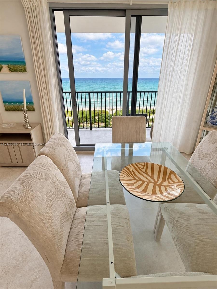 Floor-to-ceiling sliding glass door, metal balcony railing, and ocean backdrop