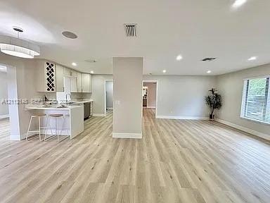 Open-concept interior featuring wood-finish flooring, a kitchen peninsula with integrated seating, built-in wine storage, recessed lighting, and a mod