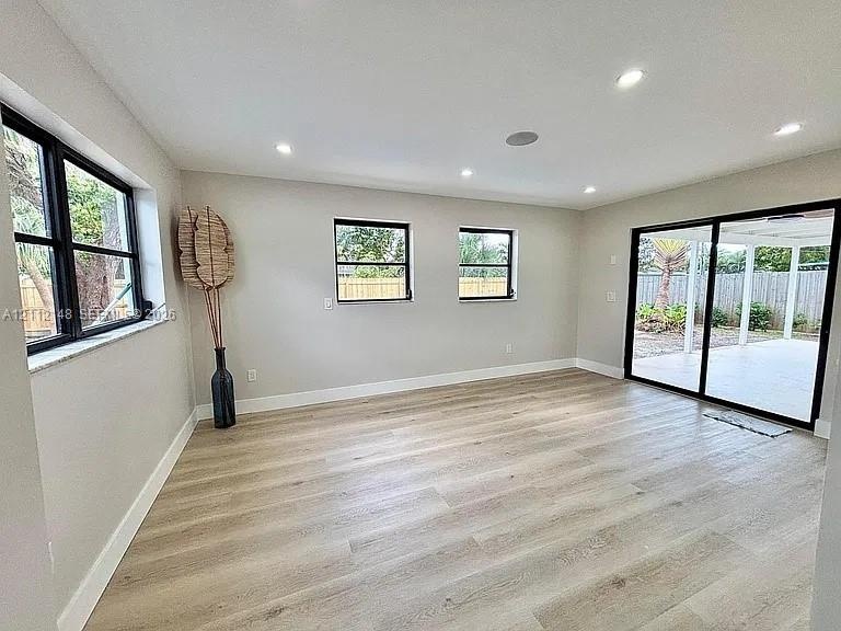 Interior space featuring wood-finish flooring, recessed lighting, black-framed windows, and sliding glass doors with direct patio access