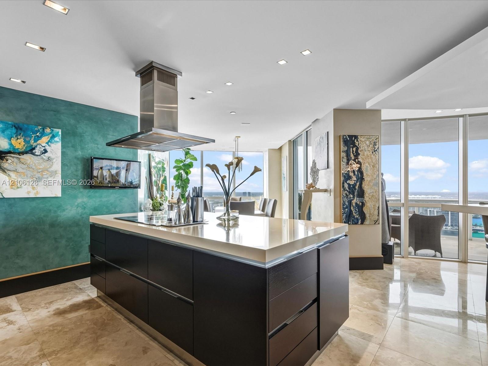 Kitchen featuring a center island with a stone countertop, dark cabinetry, a stainless steel chimney-style range hood, recessed ceiling lighting, and 