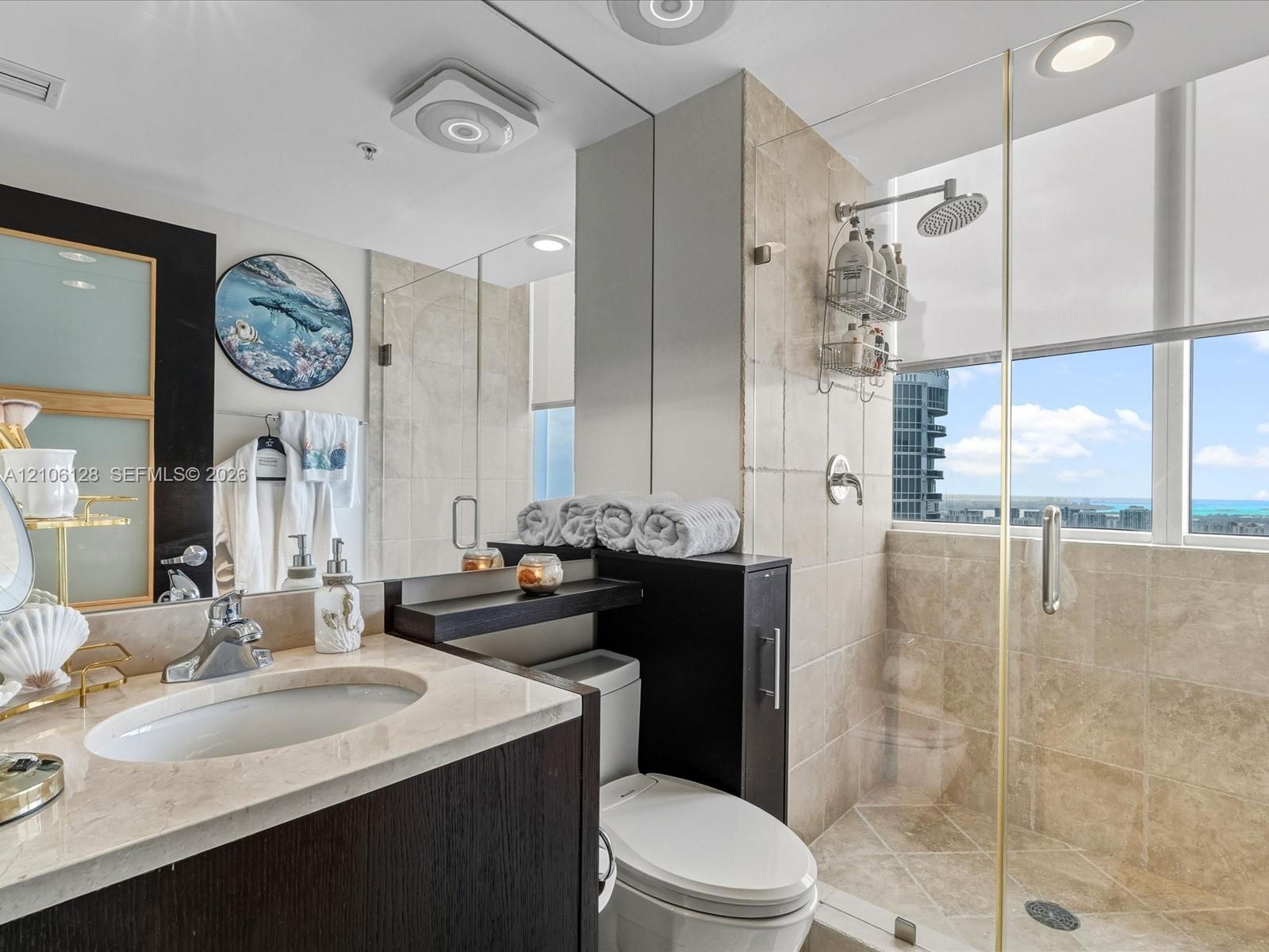 Bathroom featuring a stone-surface vanity with an integrated undermount sink, dark-finish cabinetry, floor-to-ceiling tile shower enclosure, glass par