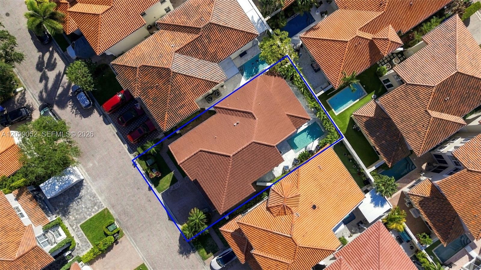 Aerial view featuring a multi-hipped tile roof, an in-ground swimming pool, and a private fenced yard with mature landscaping