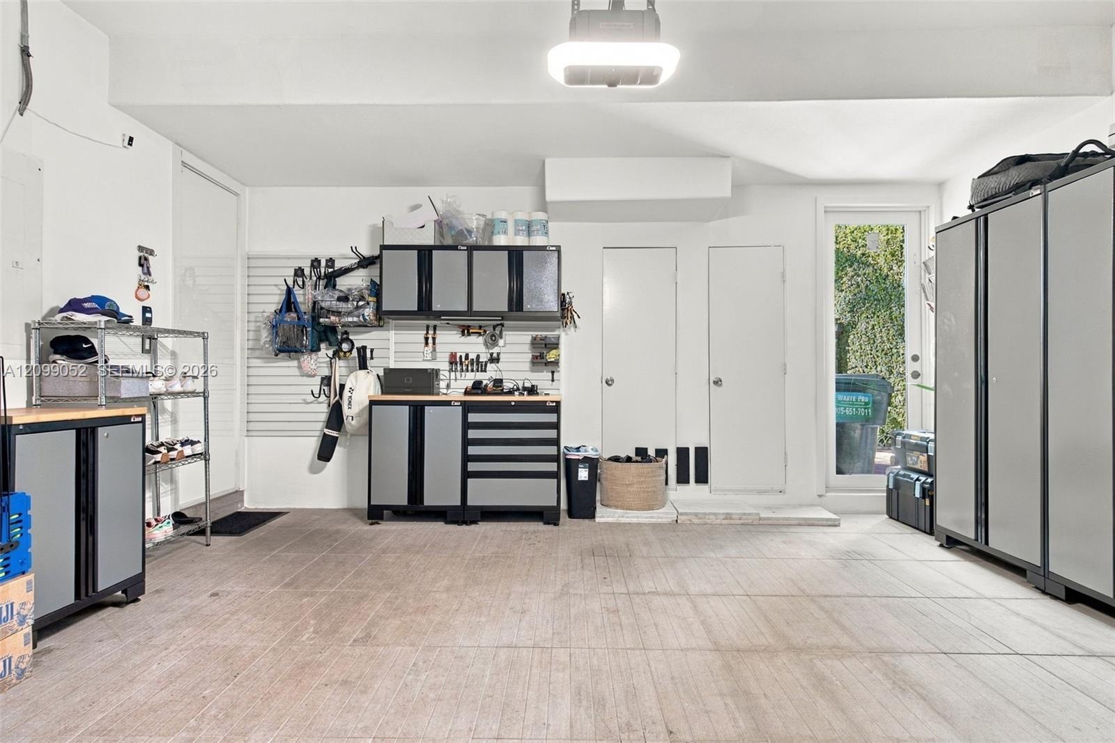 Finished garage featuring integrated wall-mounted storage panels, custom built-in cabinetry with metal-finish doors, durable concrete flooring, and a 