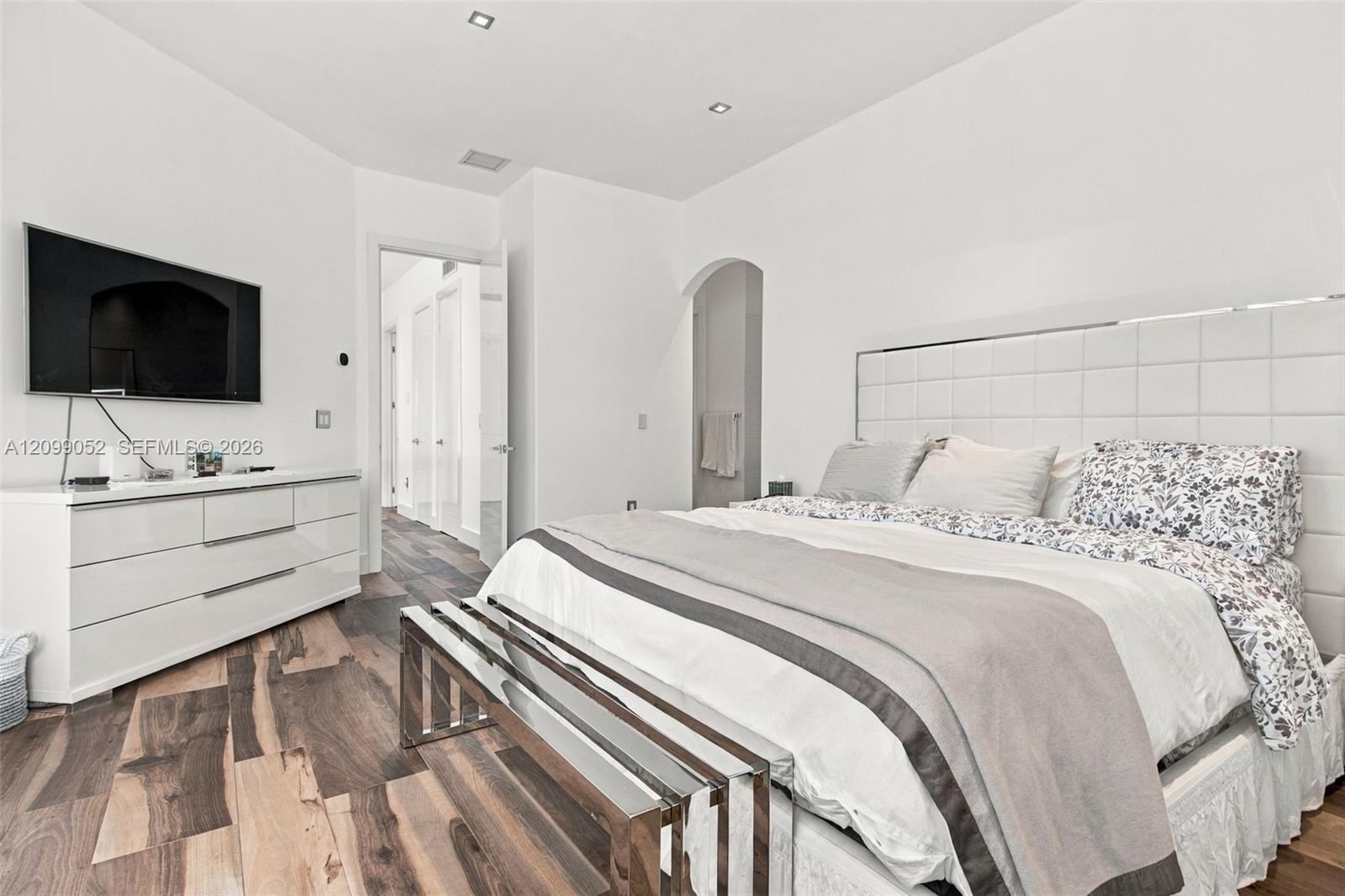 Room interior featuring wood-finish flooring, recessed lighting, and an arched doorway