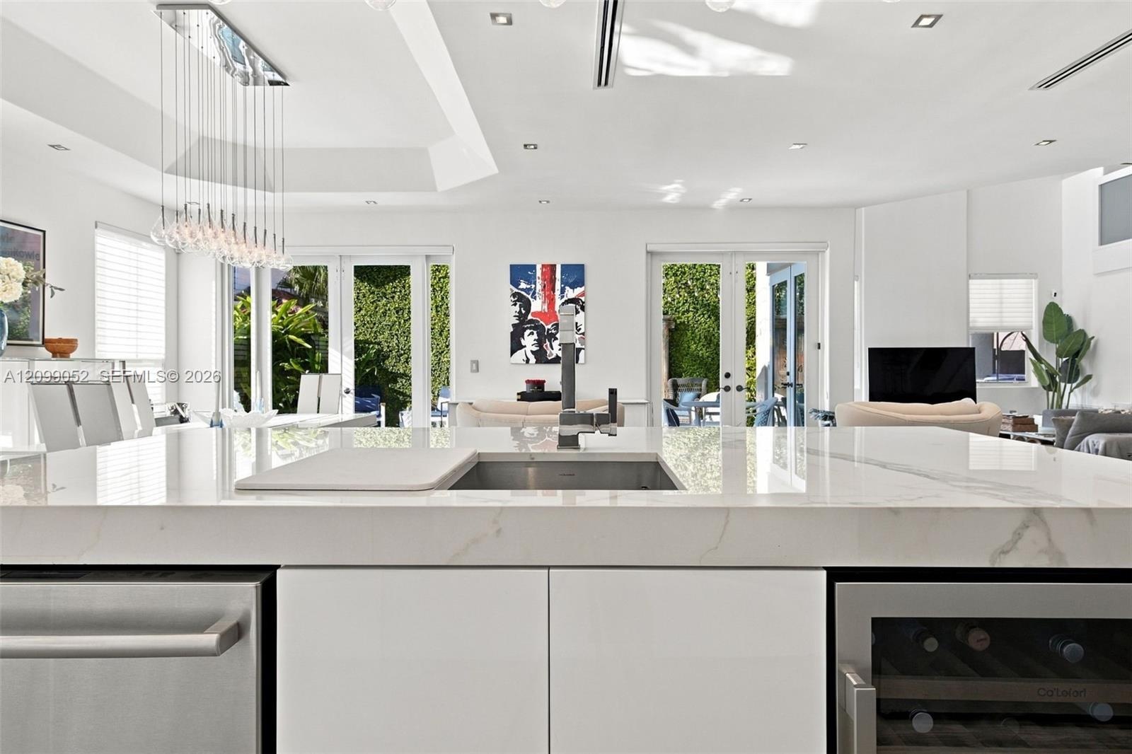 Kitchen island featuring a stone-look countertop, undermount sink with a high-arch faucet, built-in stainless steel dishwasher, integrated wine refrig