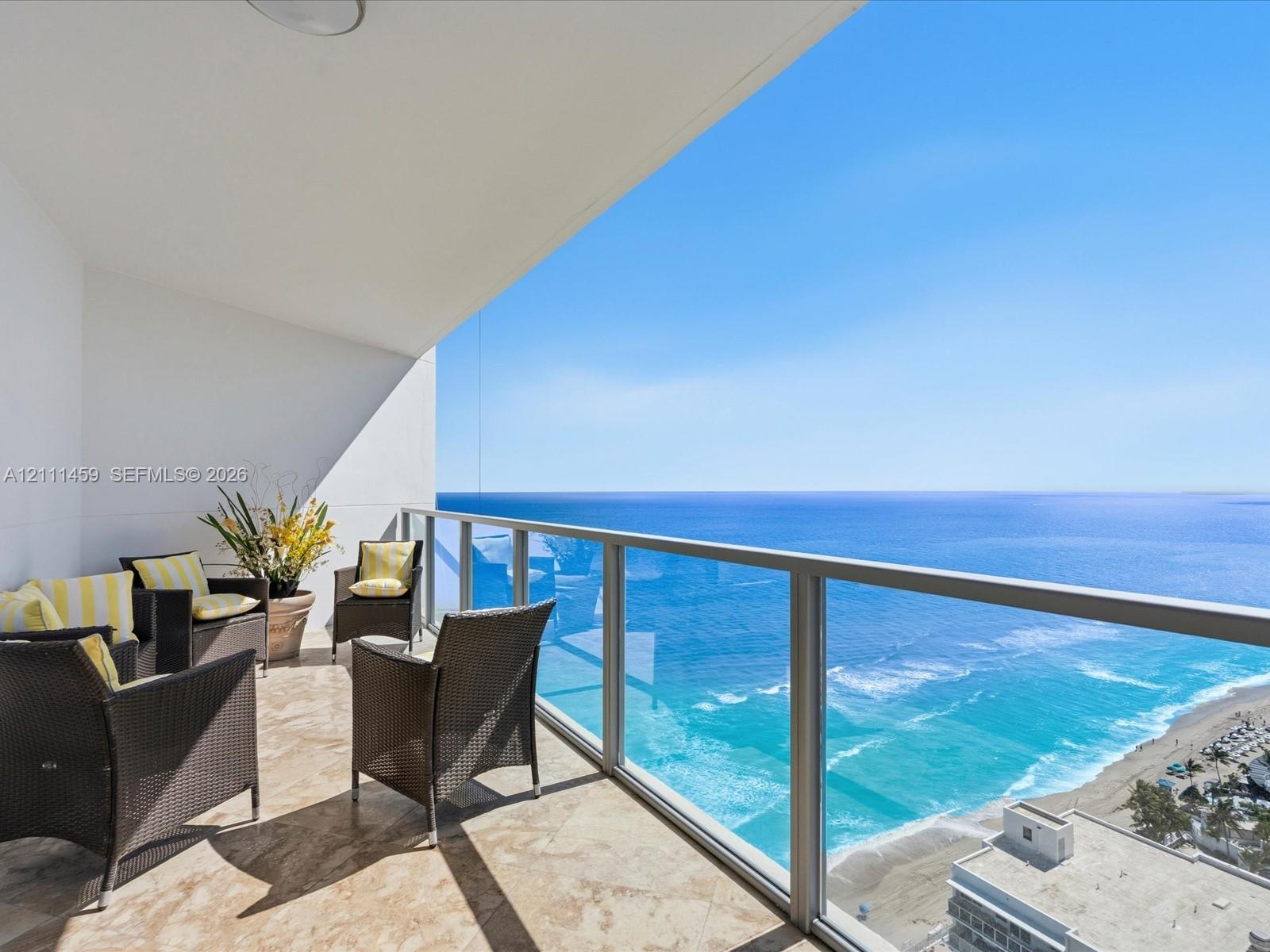Private balcony featuring natural stone flooring and a glass-paneled railing with ocean scenery