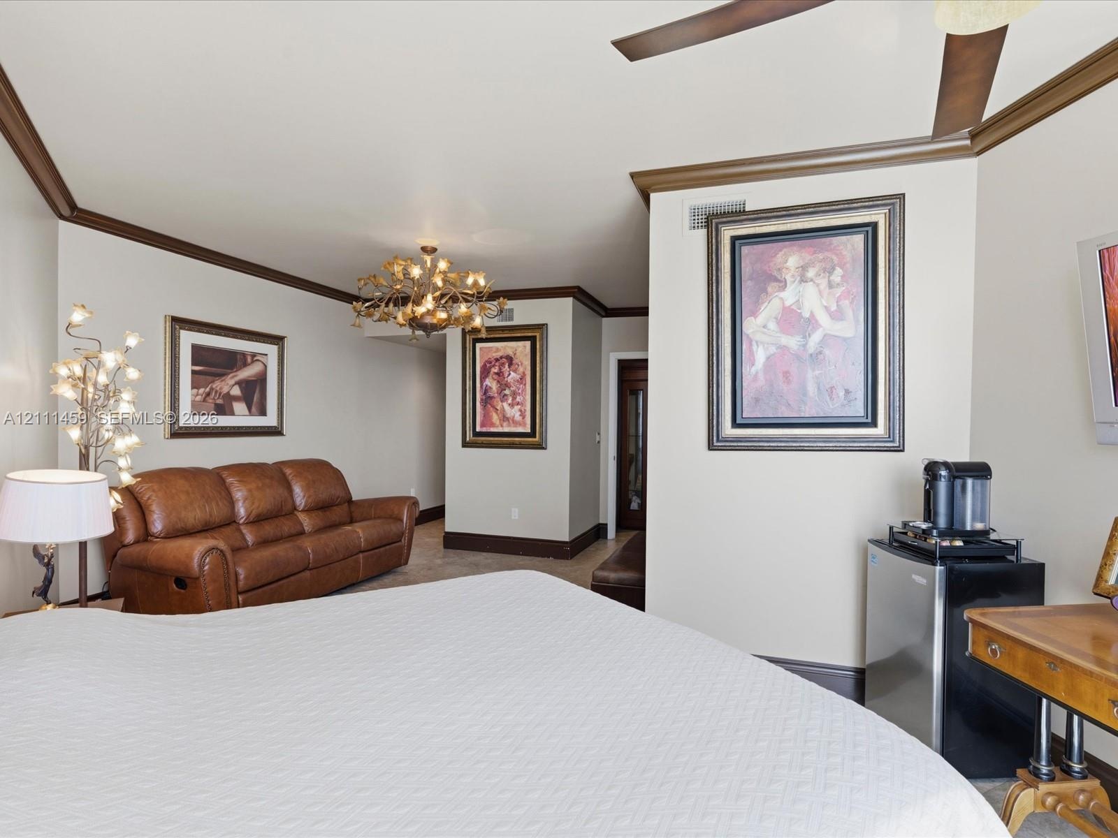 Vaulted ceilings with crown molding, decorative chandelier, and ceiling fan