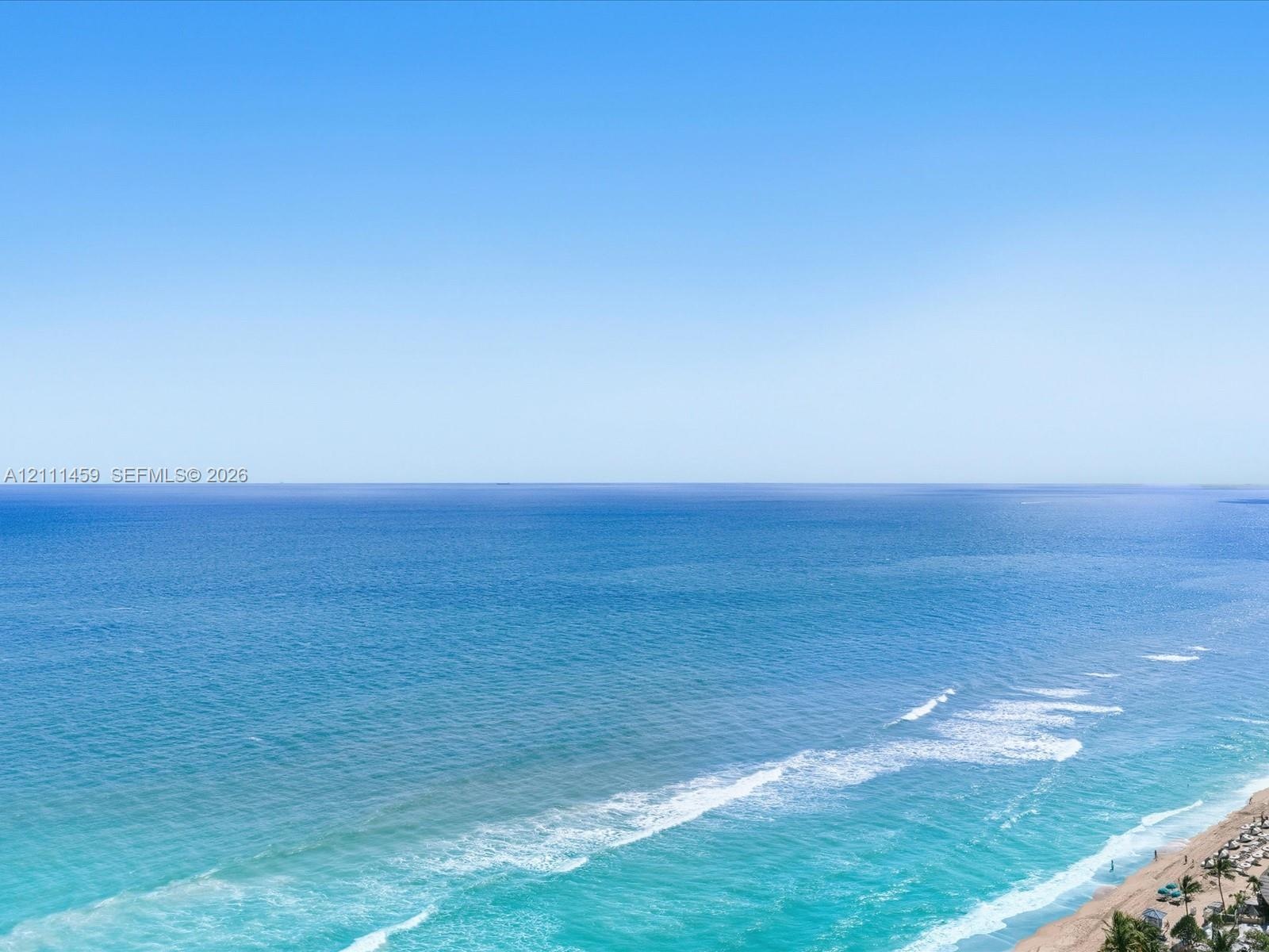 Expanse of ocean horizon with a clear sky and sandy coastline