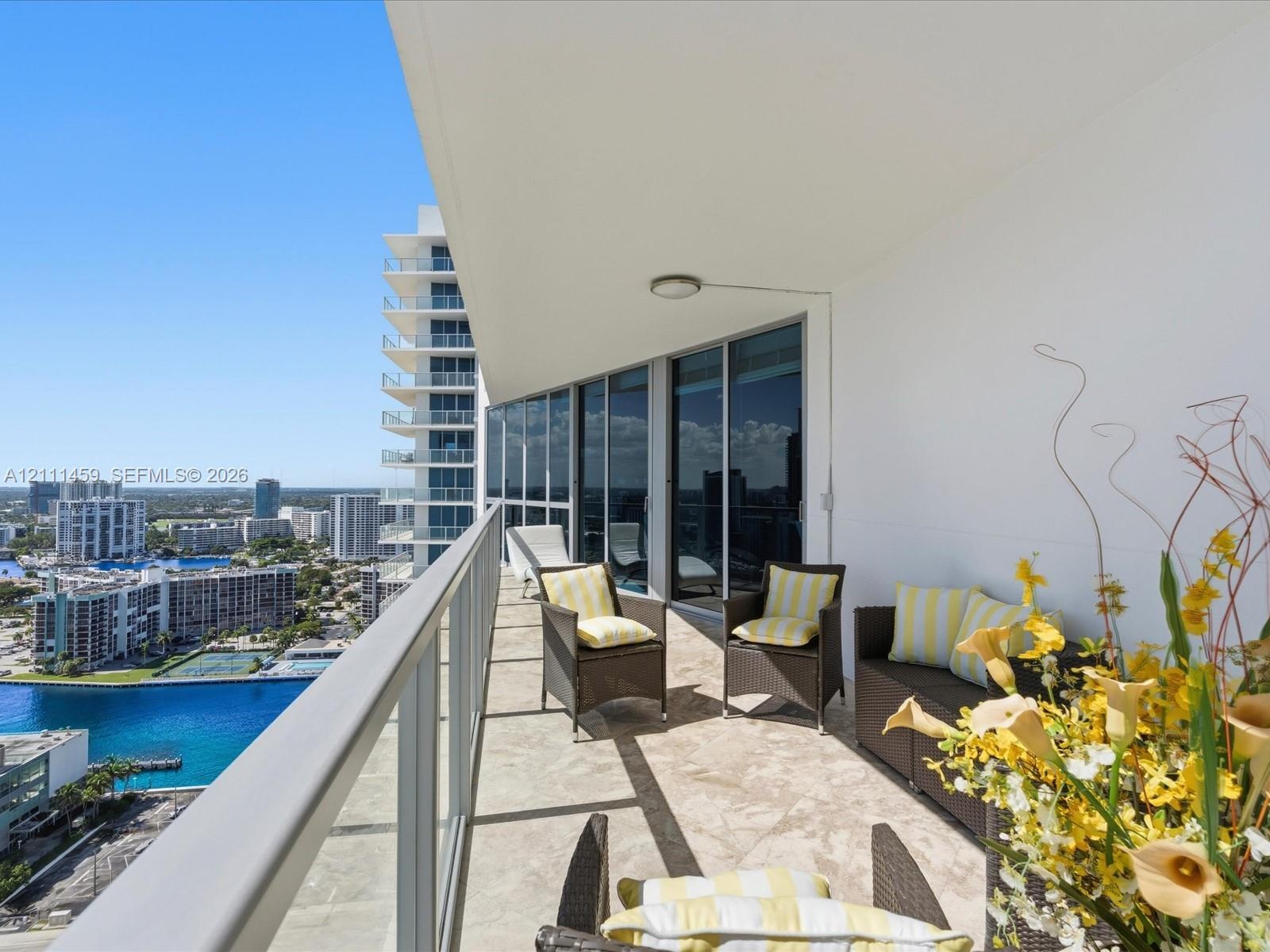 Covered balcony featuring stone-finish flooring, a glass-panel railing, and floor-to-ceiling sliding glass doors