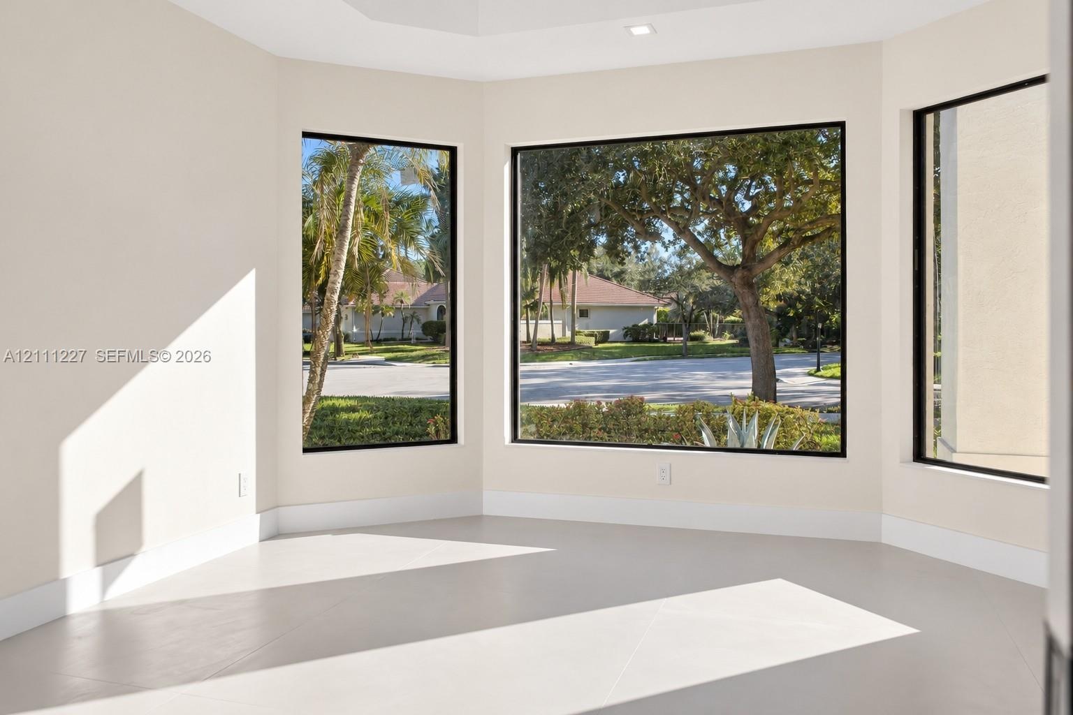 Expansive room featuring a multi-panel window bay, neutral wall finishes, recessed ceiling lighting, and large-format tile flooring