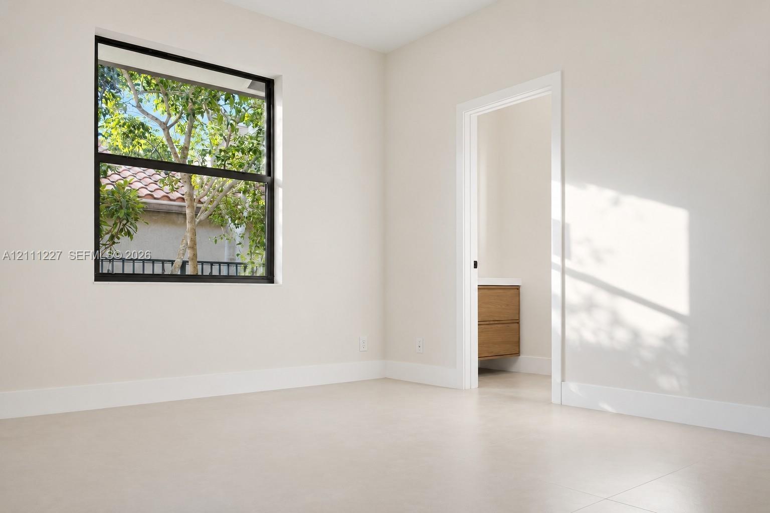 Neutral-toned interior space featuring a large window with black framing and light-colored flooring