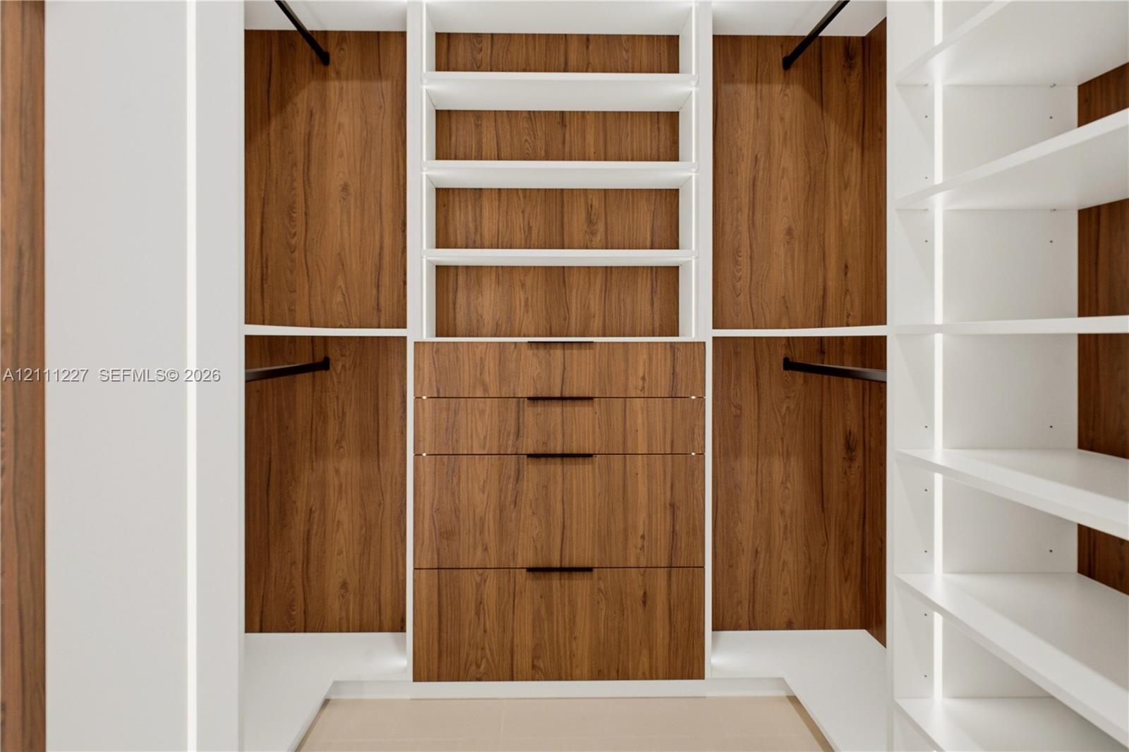 Custom walk-in closet featuring wood-finish cabinetry, built-in shelving, integrated hanging rods, and a four-drawer dresser unit with matte hardware