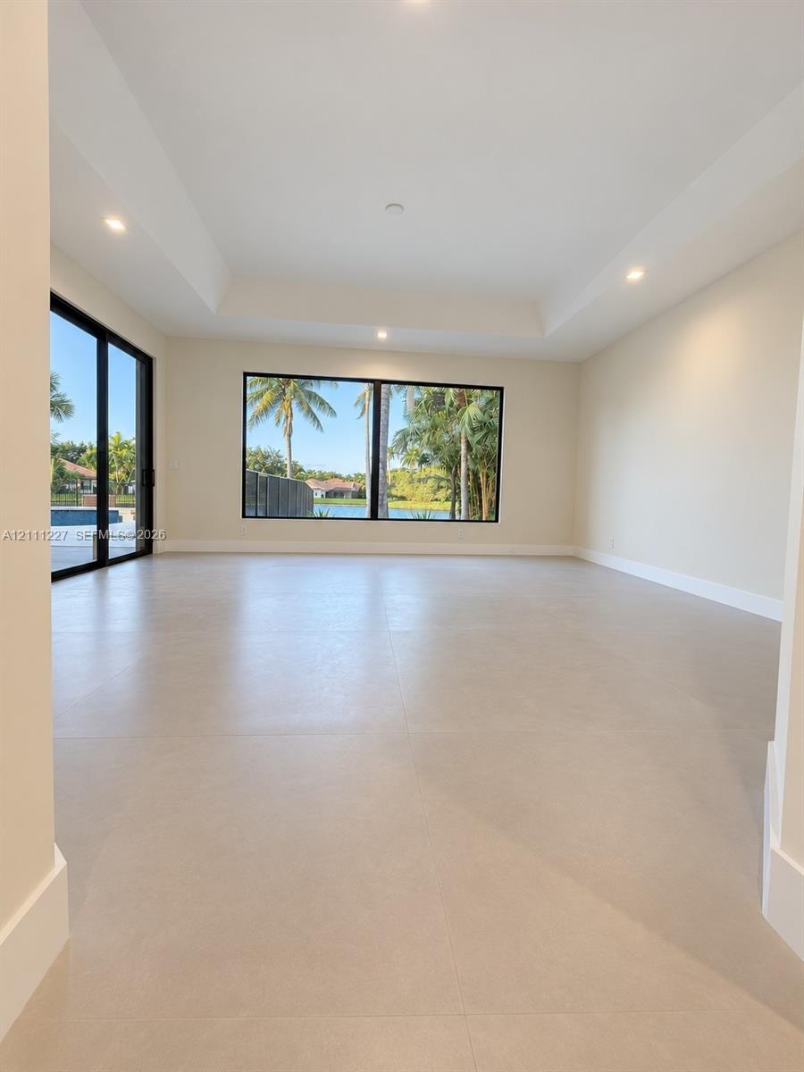 Interior space featuring large-format tile flooring, tray ceilings, recessed lighting, expansive glass sliding doors, and oversized windows