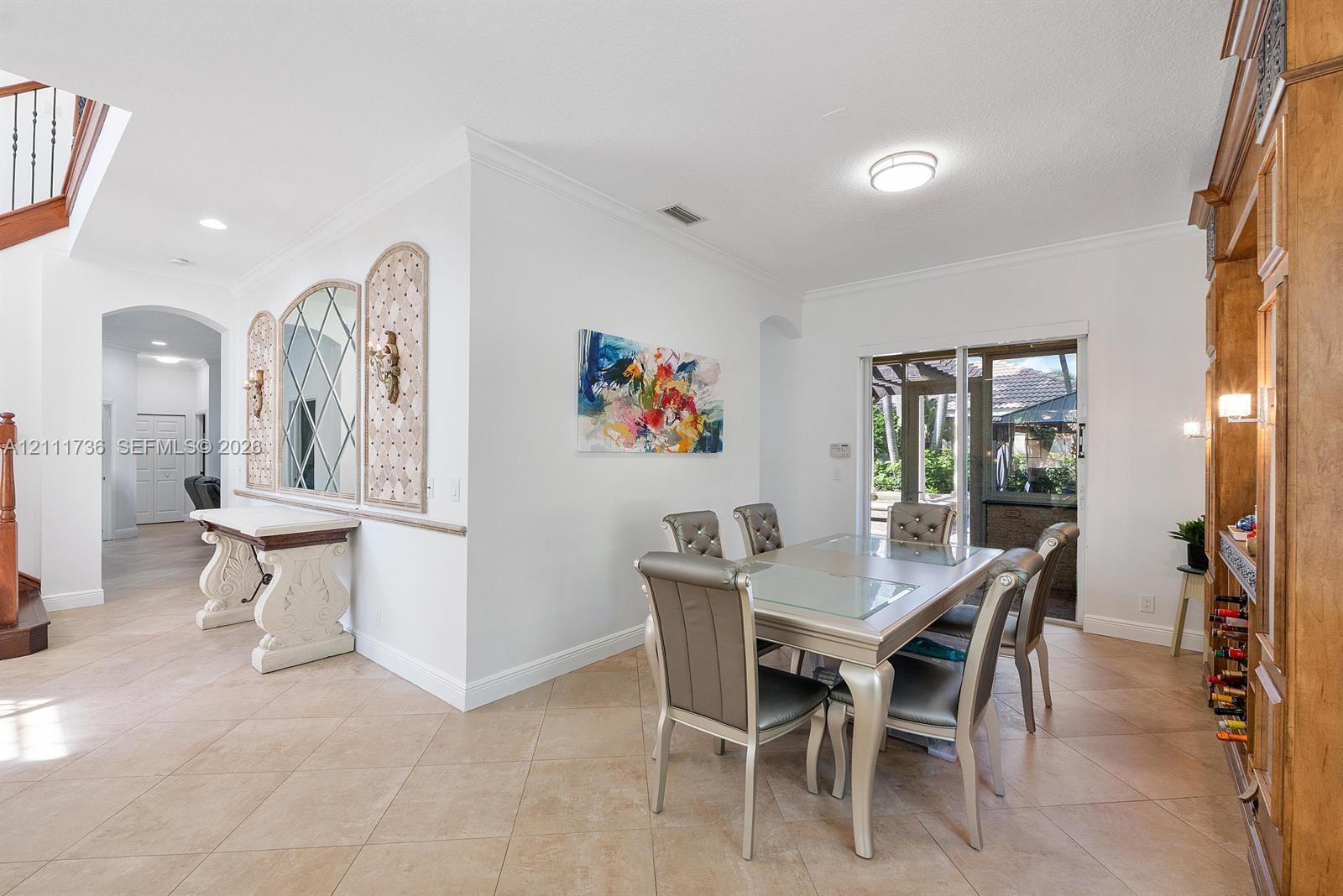 Dining area featuring diagonal tile flooring, built-in floor-to-ceiling wood cabinetry, decorative wall mirror with geometric inlay, and sliding glass