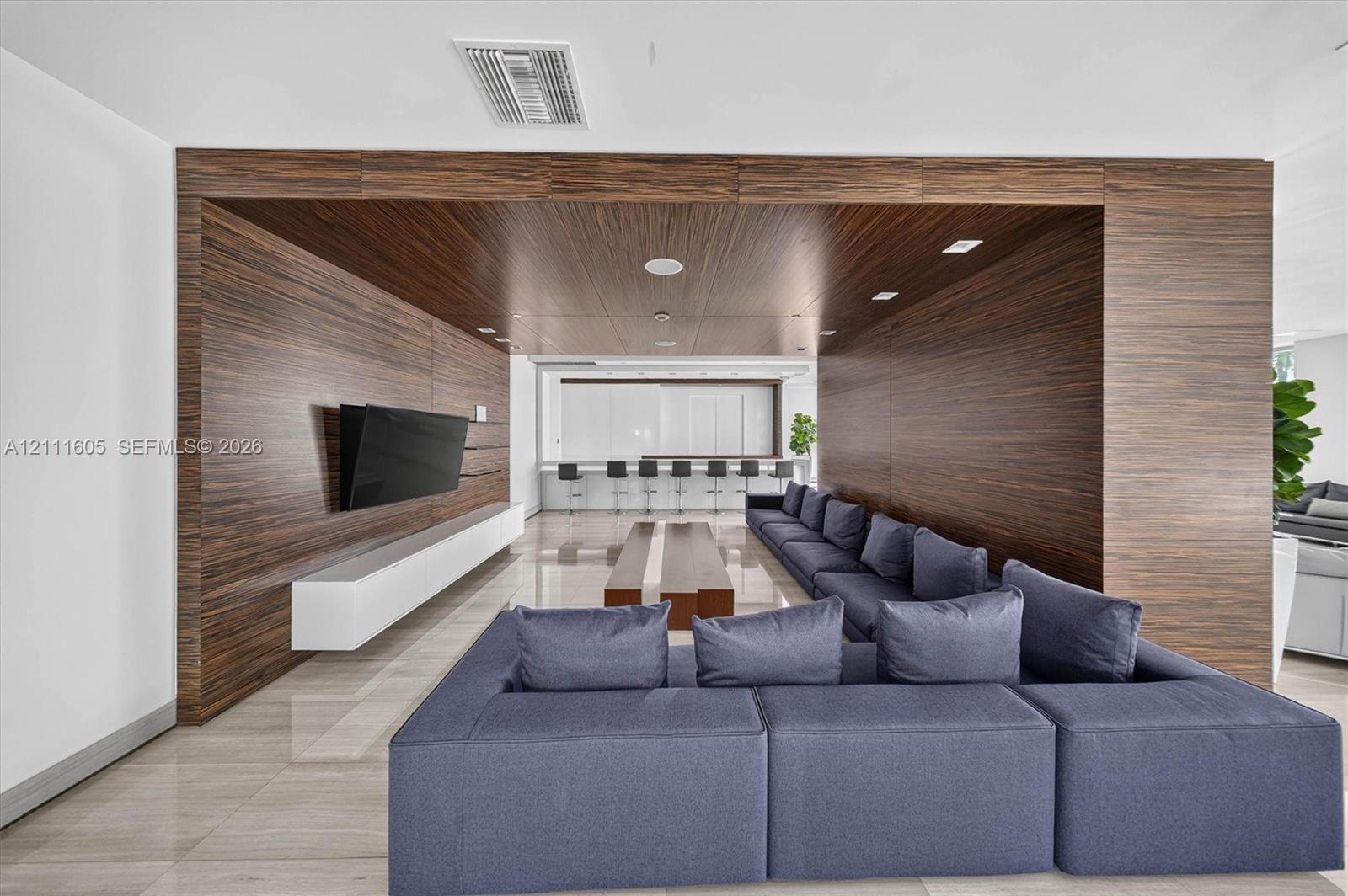 Floor-to-ceiling sliding glass doors opening to a balcony, wood-panel wall accents, recessed linear lighting, and modern pendant fixture