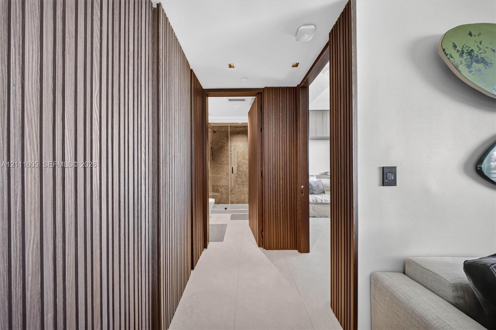 Bathroom featuring floor-to-ceiling textured stone wall tiles, wood-finish vanity with a stone countertop, integrated sink, and glass-enclosed shower 