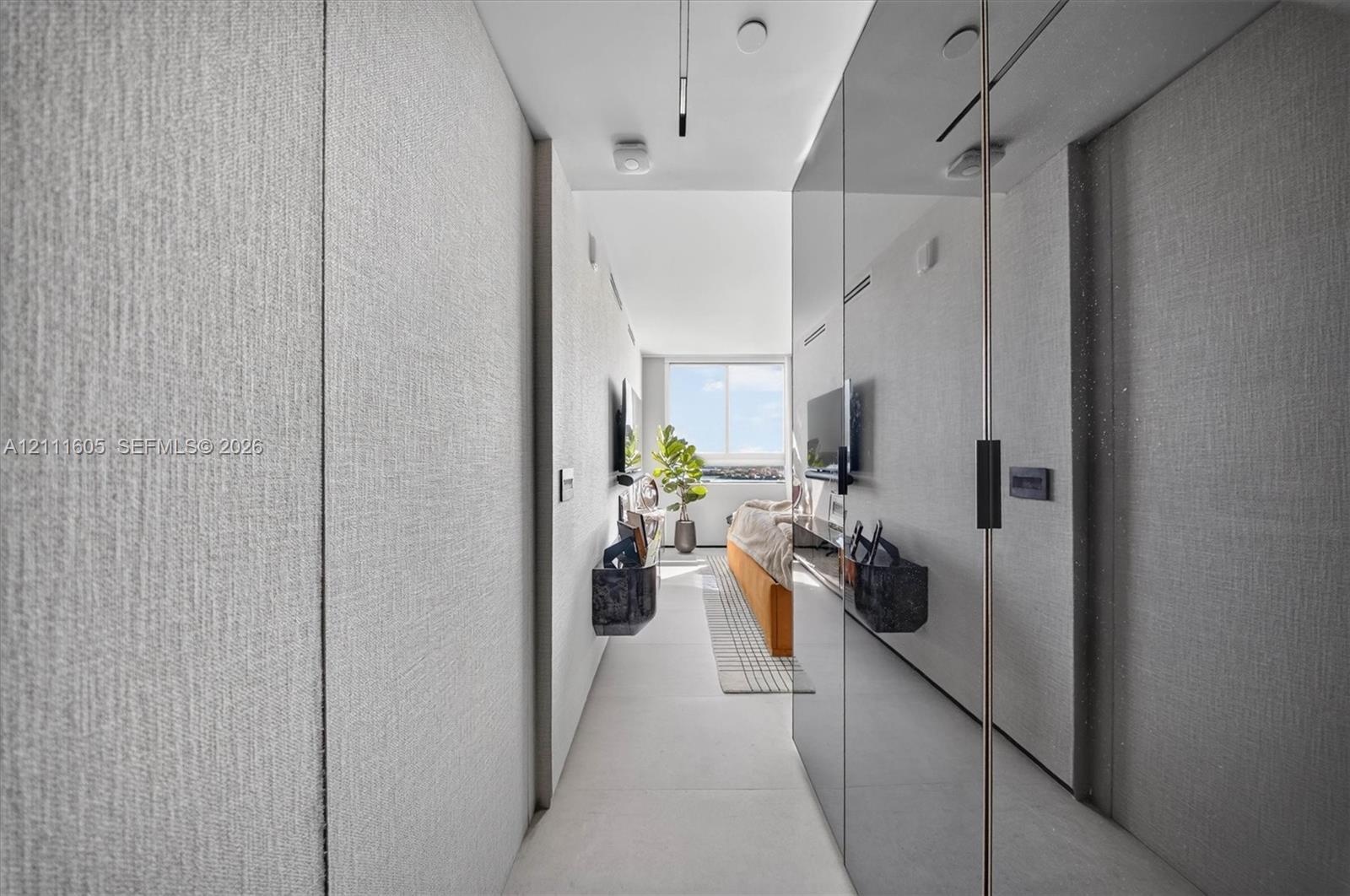 Walk-in shower with frameless glass enclosure, matte black fixtures, integrated wall shelving, floor-to-ceiling stone tile, and vertical wood-finish p