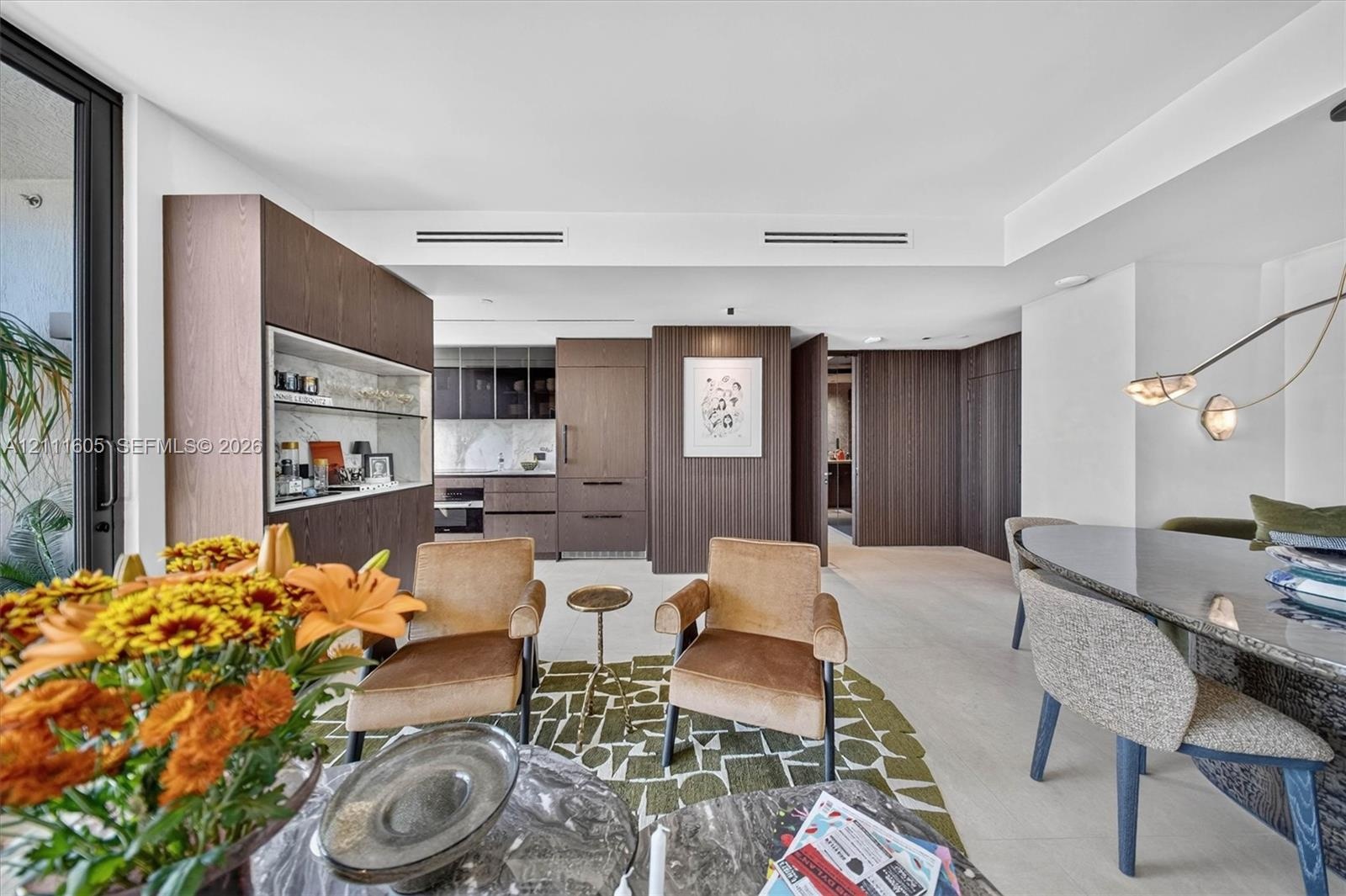 Custom floor-to-ceiling upholstered wall paneling, floating dark-stone finish bedside tables, large-format window, and minimalist disc-style wall scon