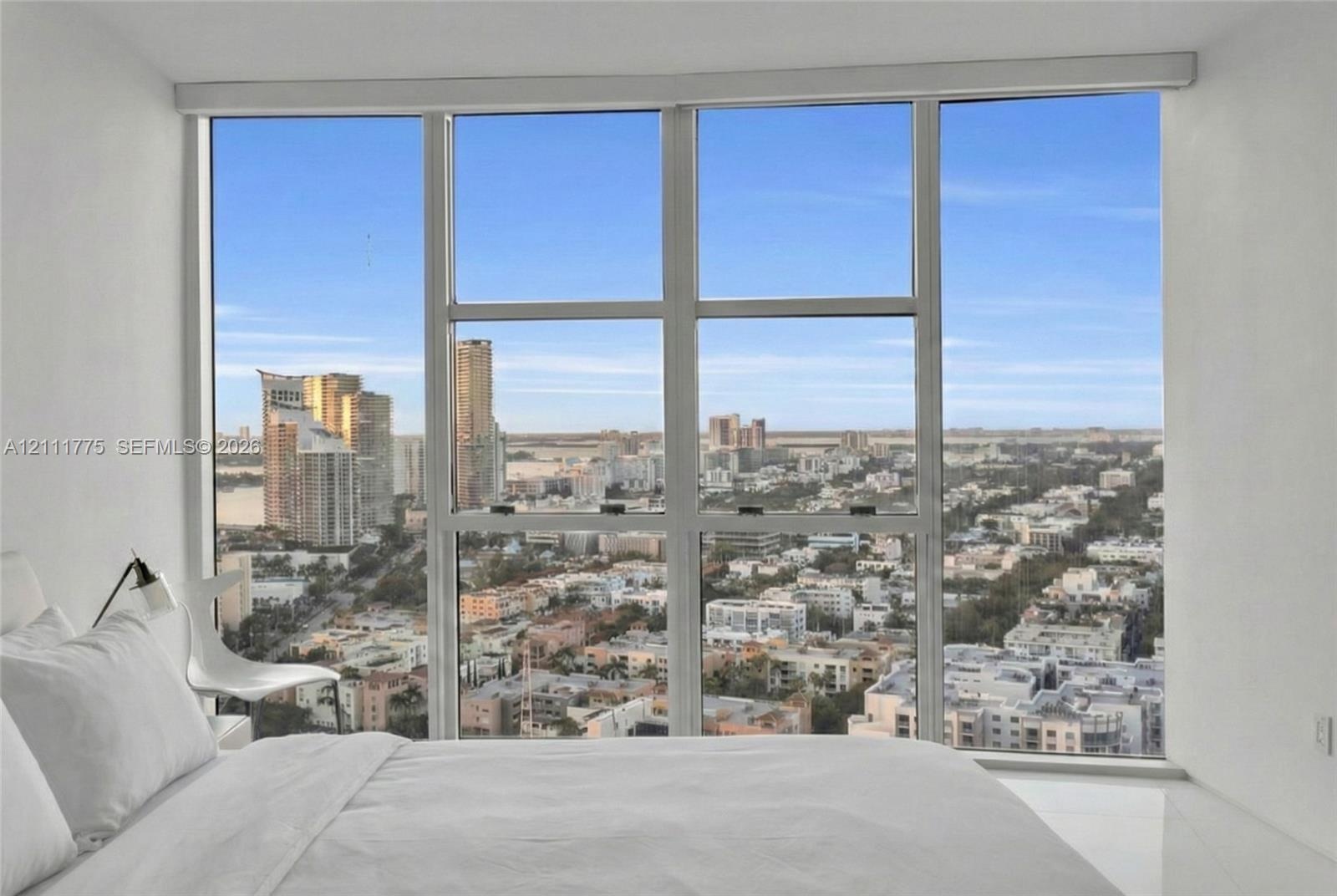 Floor-to-ceiling windows featuring expansive urban panoramas, sleek white walls, and polished flooring
