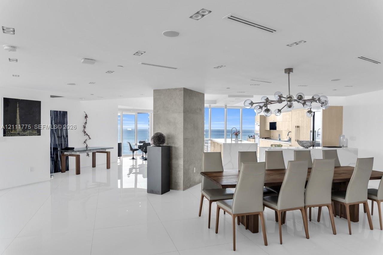 Open-concept living space featuring high-gloss tile flooring, floor-to-ceiling windows with ocean scenery, a central concrete pillar, recessed lightin