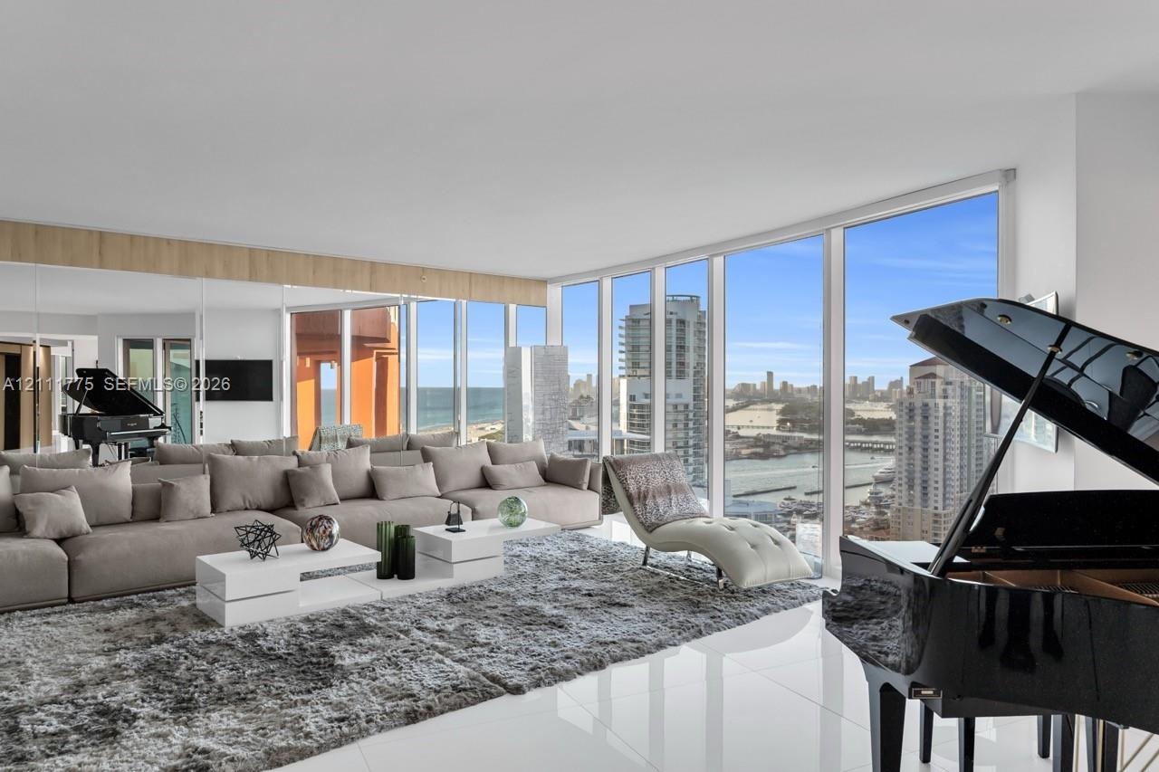 Floor-to-ceiling windows featuring panoramic urban and water scenery, polished white tile flooring, and mirrored wall accents