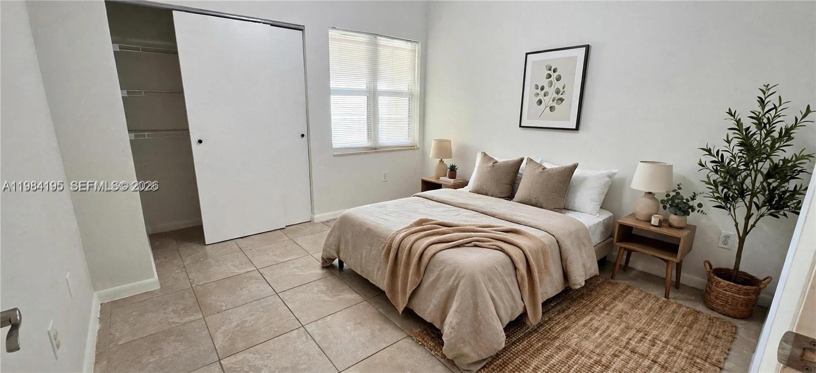 Neutral-toned ceramic tile flooring, sliding-door closet, and natural light via multi-pane window