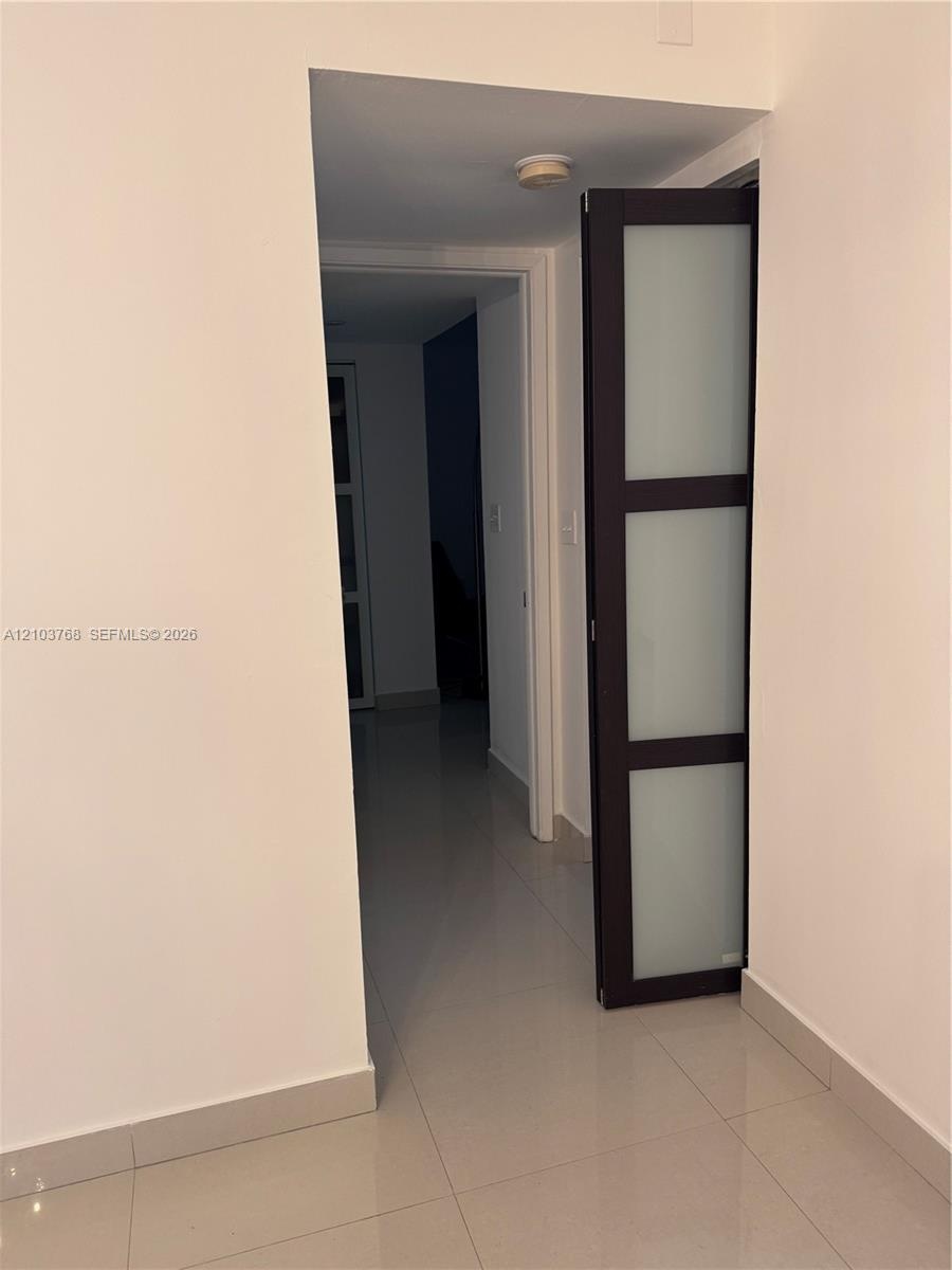 Dark-framed door with three frosted glass panels and high-gloss tile flooring