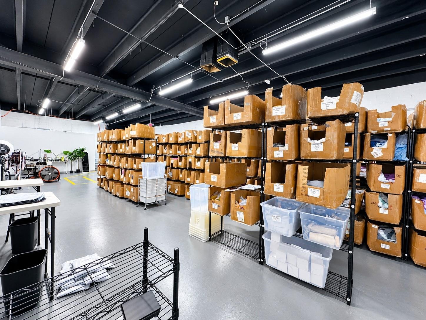 Industrial-style workspace featuring an expansive open floor plan, exposed dark-toned ceiling joists, durable floor coating, and high-output linear li