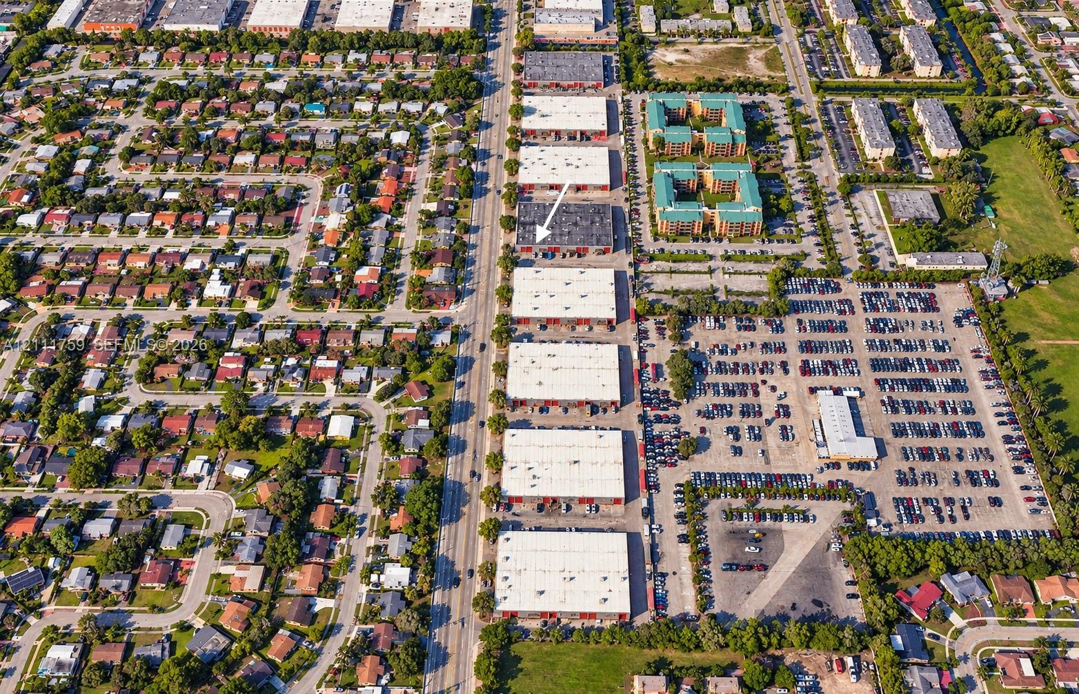 Aerial perspective of a multi-unit industrial complex featuring flat roof architecture, paved surface parking, and direct street access