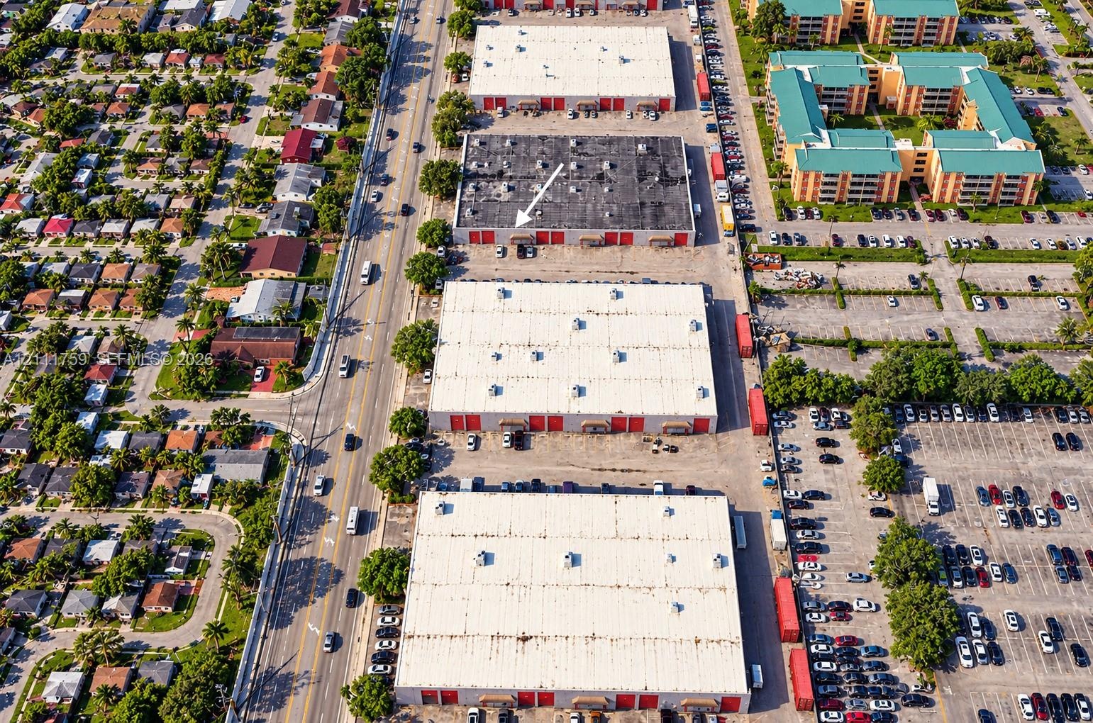 Aerial perspective of industrial warehouse complex featuring paved parking areas, multi-bay loading access, flat roof systems, and proximity to major 