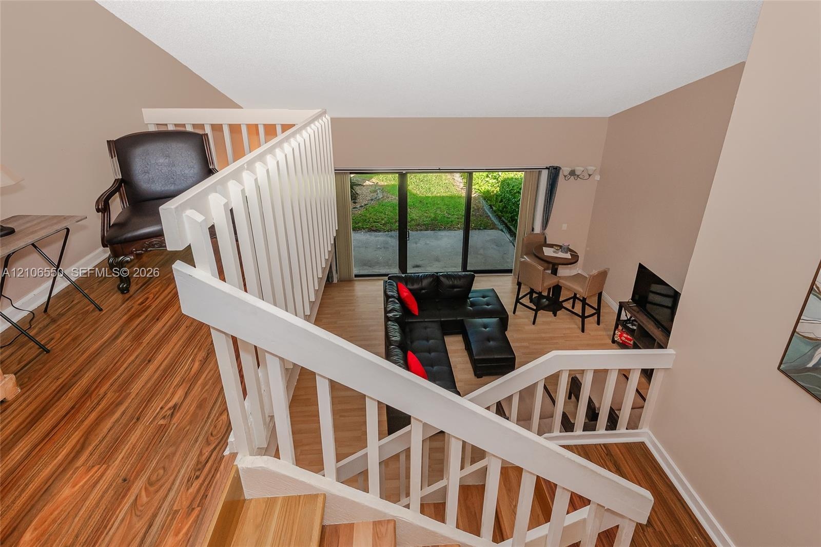 Elevated loft featuring a white wooden staircase railing and wood-finish flooring