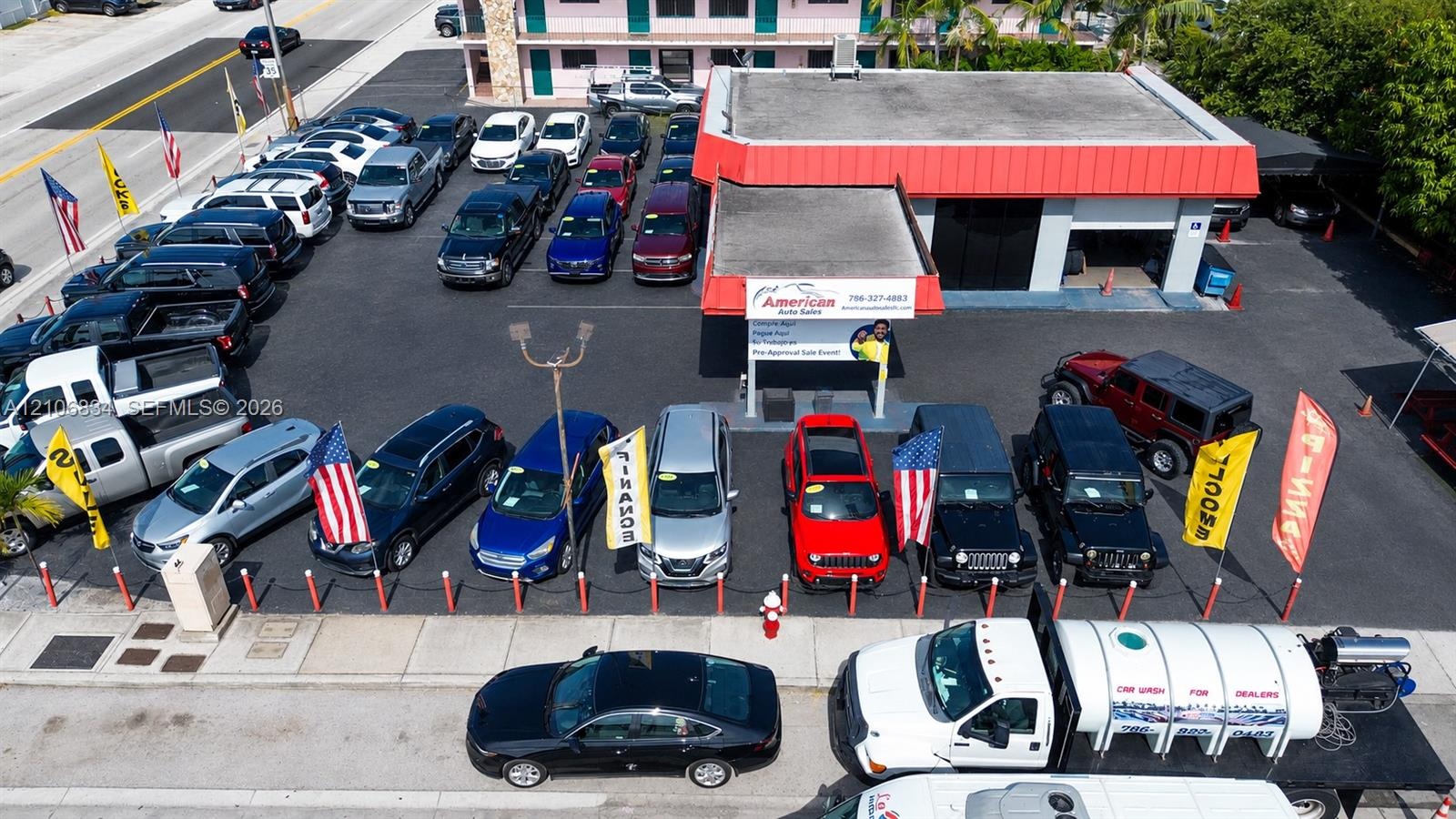 Commercial property featuring an asphalt-paved lot, a flat-roof structure with a covered service bay, and prominent street-level frontage