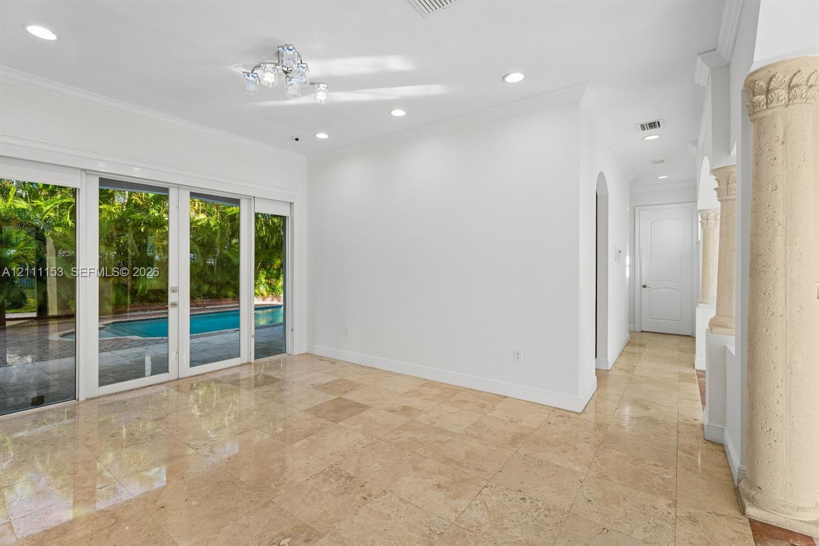 Interior space featuring polished stone flooring, recessed lighting, decorative columns, and floor-to-ceiling sliding glass doors with exterior pool e