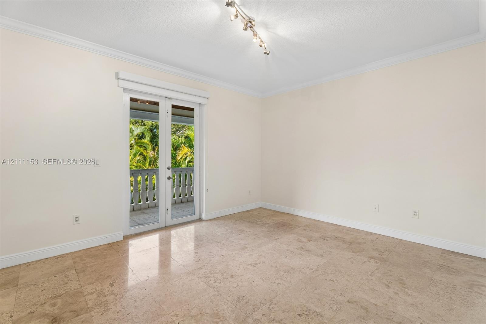 Interior space featuring natural stone tile flooring, crown molding, a multi-bulb track lighting fixture, and French doors opening to an exterior balc