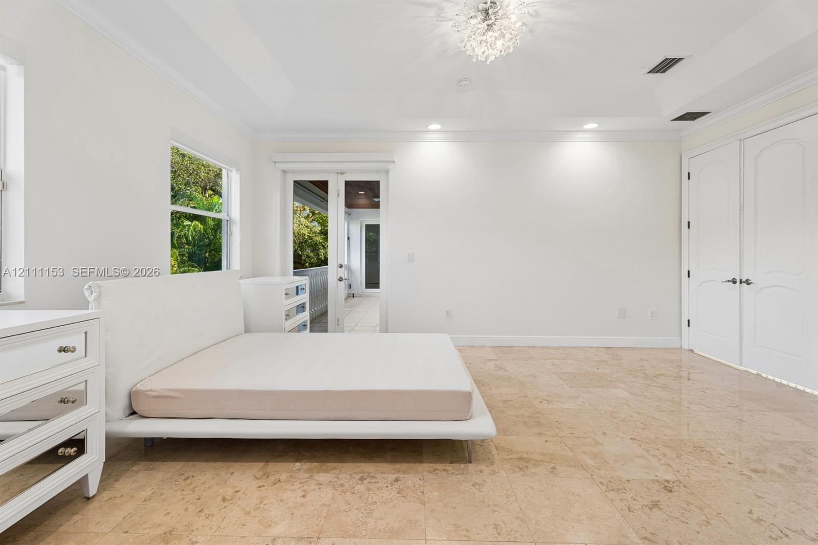 Tray ceiling featuring a decorative chandelier, polished stone flooring, and dual French doors