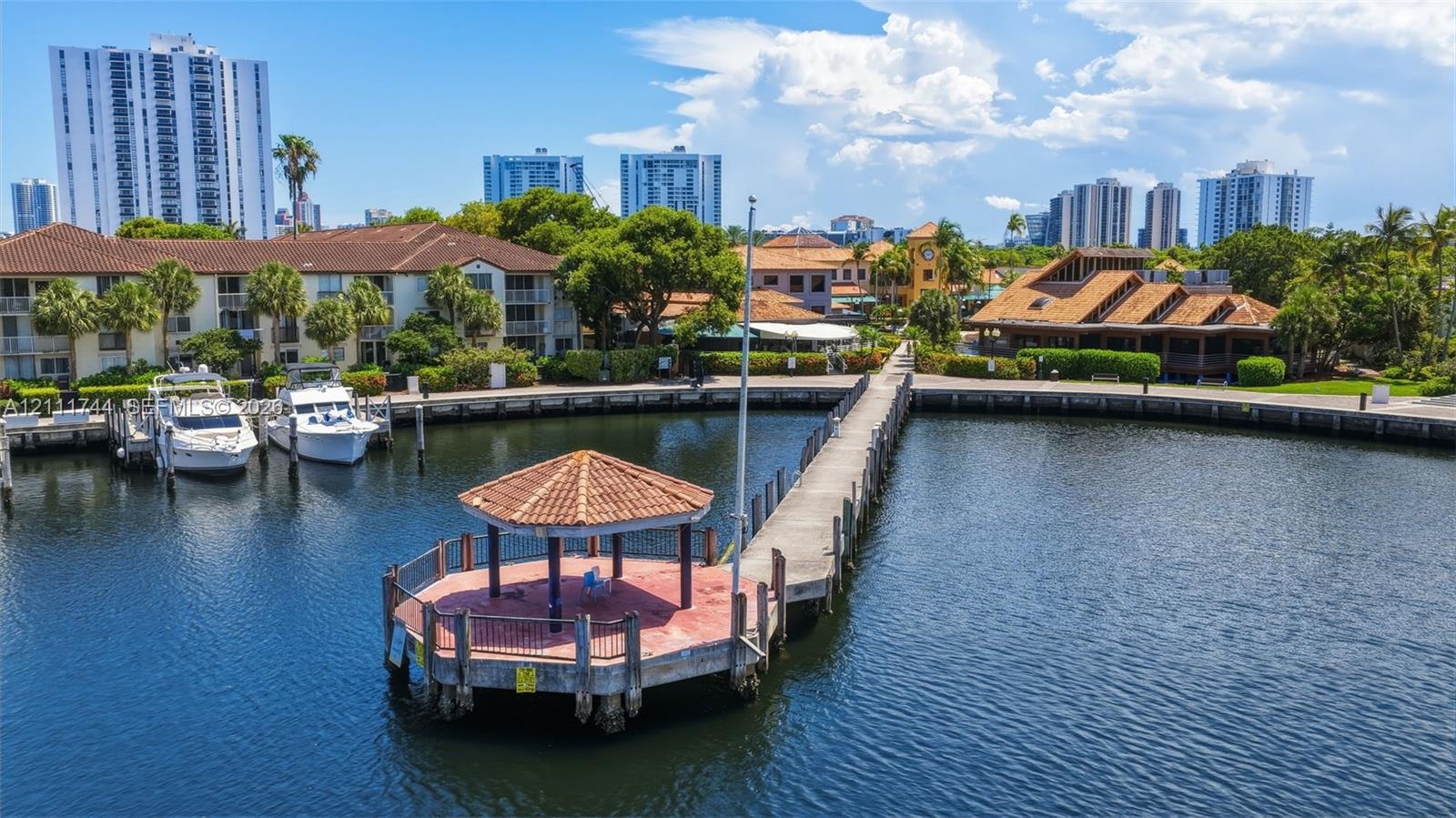 Waterfront gazebo with a clay tile roof, concrete pier, and dedicated boat slips