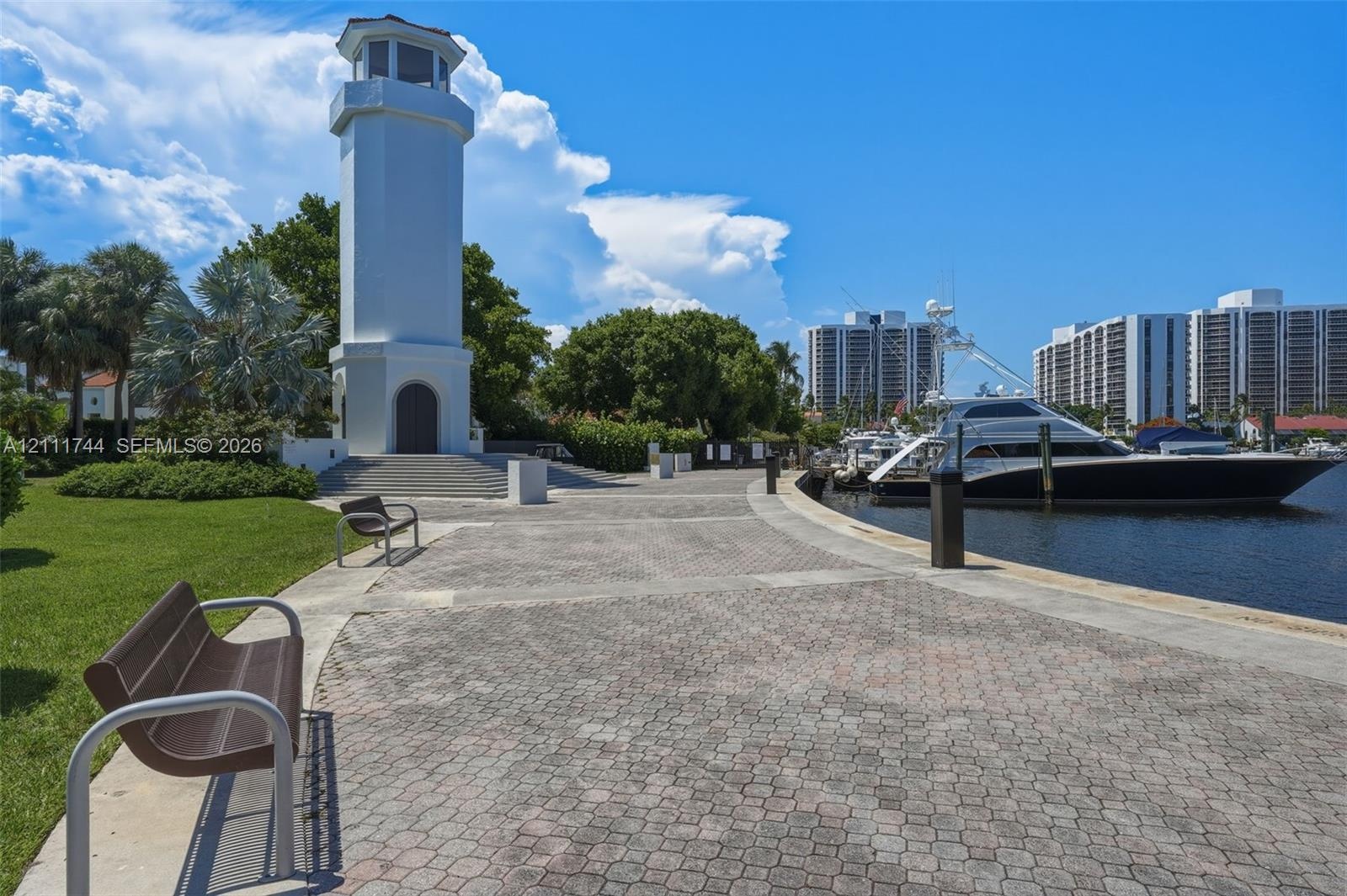 Waterfront promenade featuring a stone-paver walkway, a lighthouse-style architectural tower, and direct water access