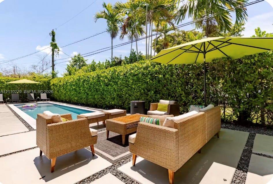 Outdoor swimming pool surrounded by concrete paver hardscaping and mature privacy hedges