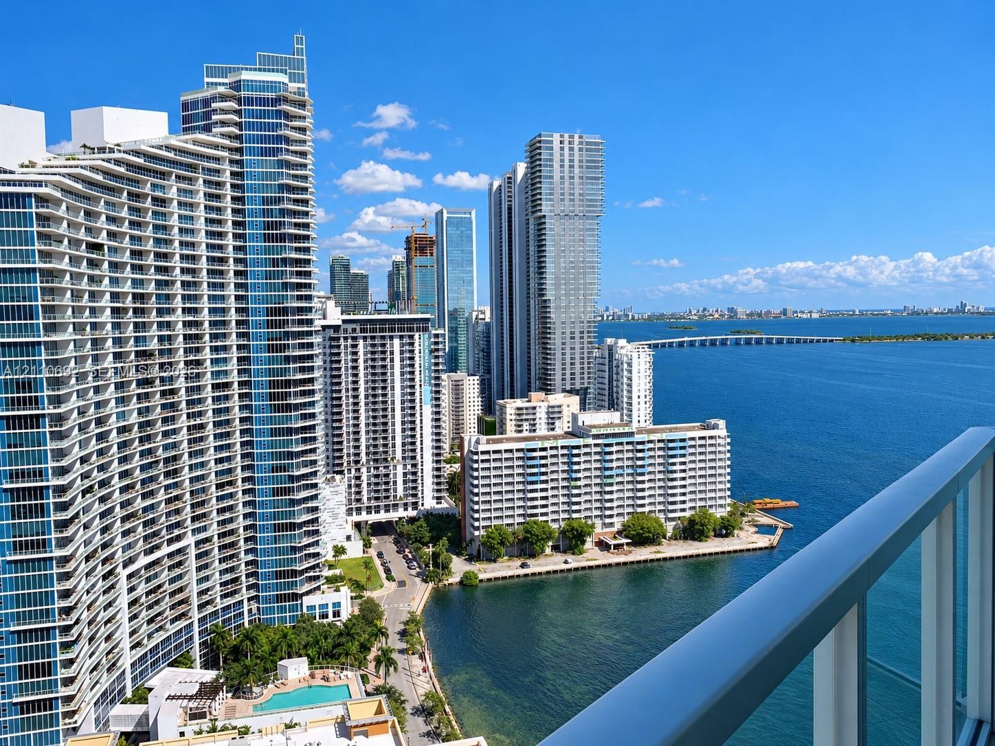 Private balcony featuring a glass and metal railing, overlooking the coastal skyline and harbor