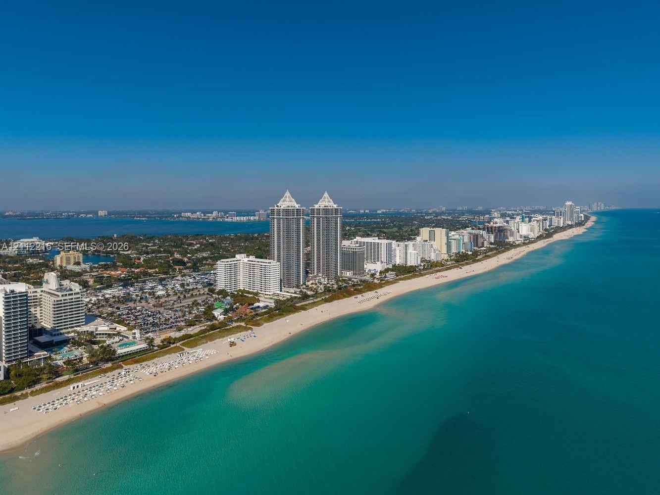 Aerial perspective of a coastal environment featuring extensive sandy beaches, expansive shoreline, and direct proximity to open water