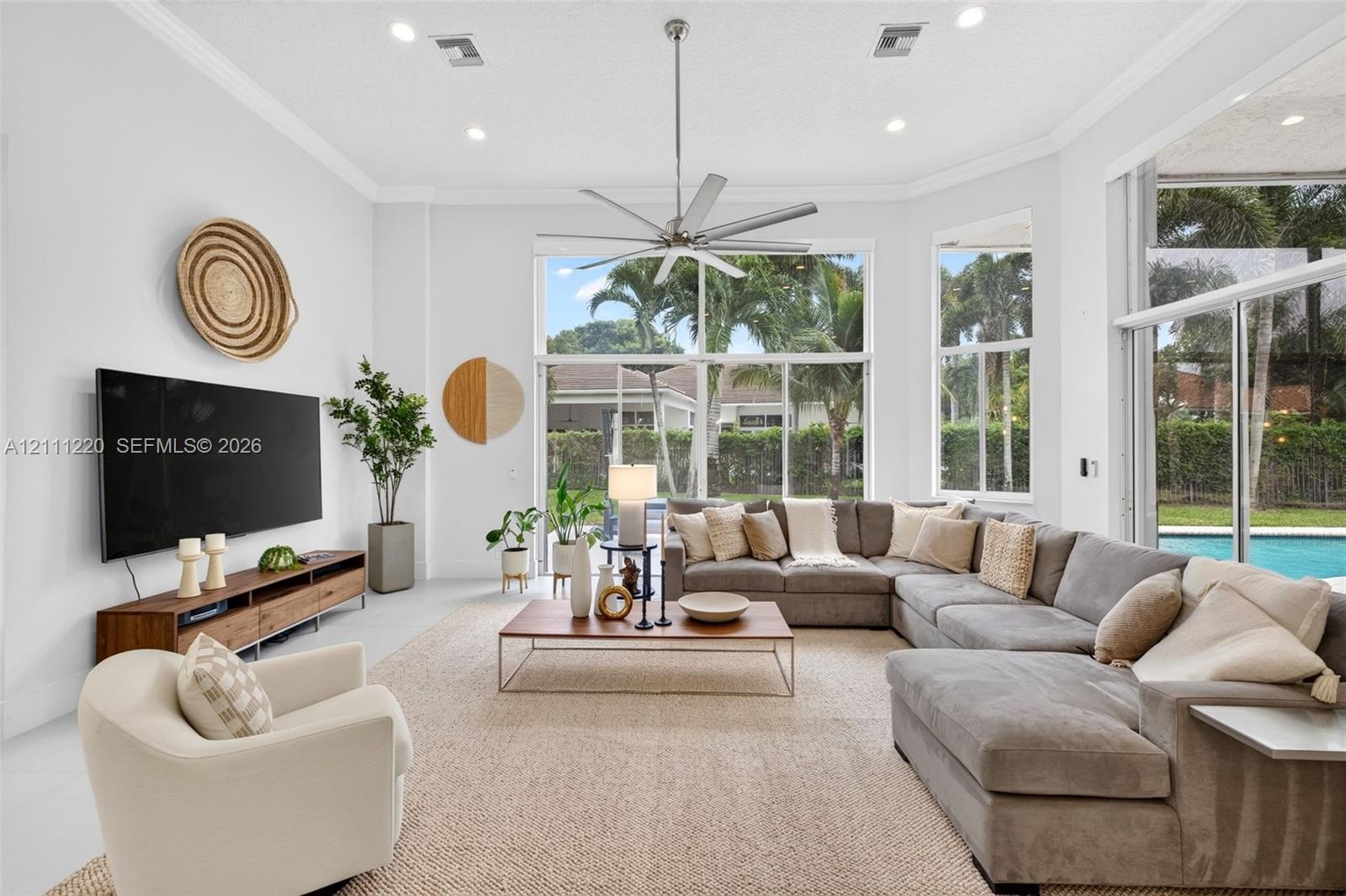 Living space featuring high ceilings, recessed lighting, crown molding, a central ceiling fan, and floor-to-ceiling windows with sliding glass doors