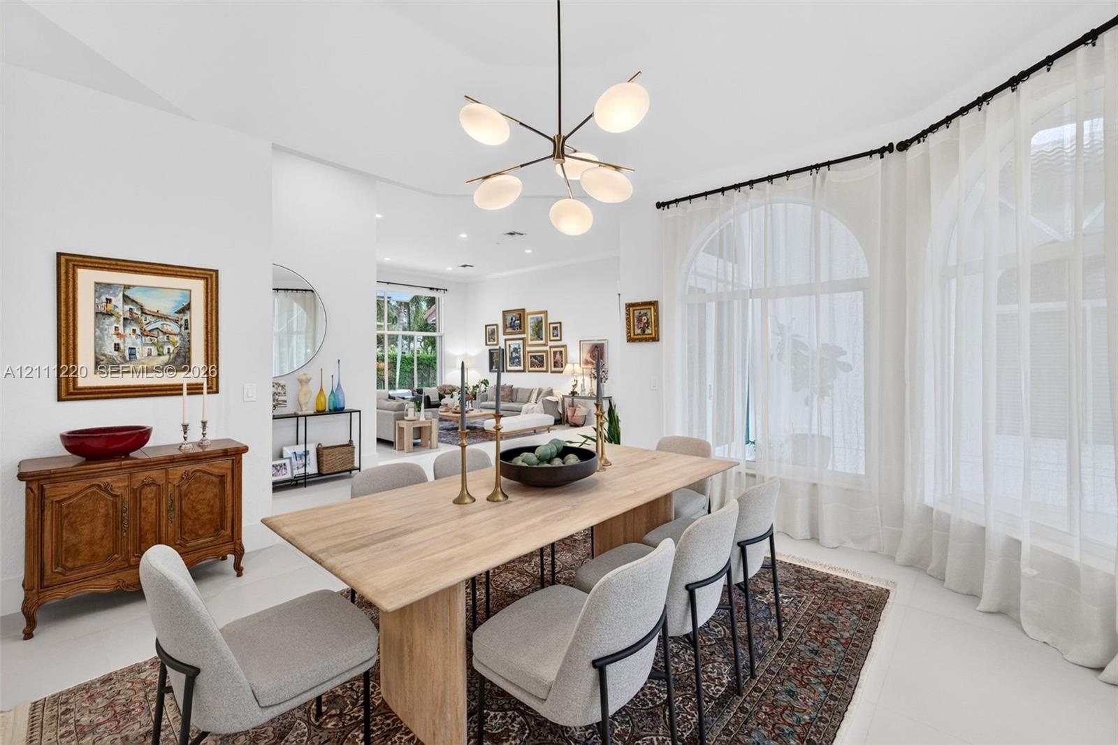 Dining space featuring arched windows, light-toned flooring, and a multi-arm modern chandelier