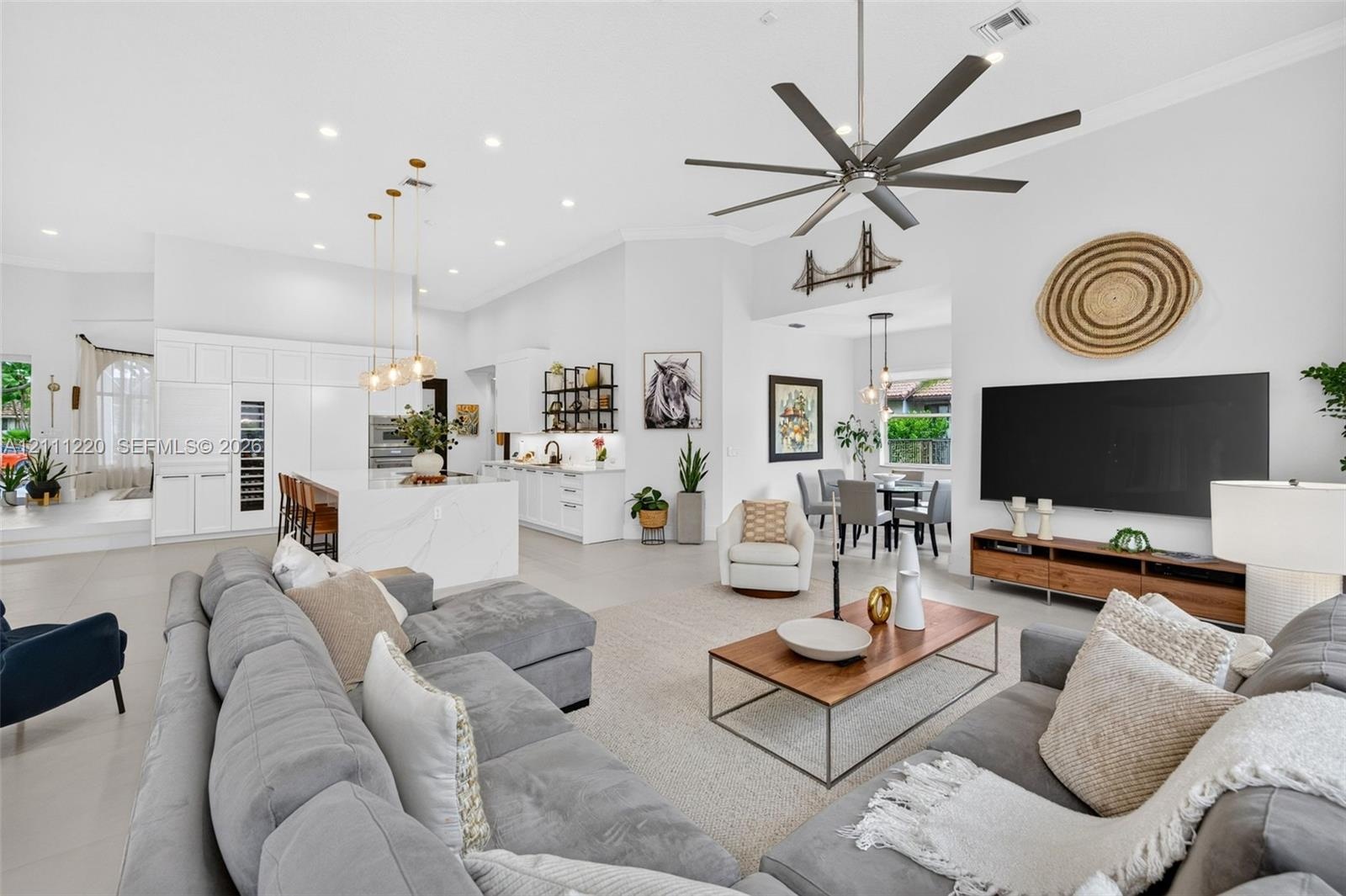 Open-concept living space featuring high ceilings, a center island with waterfall-edge countertop, recessed lighting, multi-blade ceiling fan, and lar