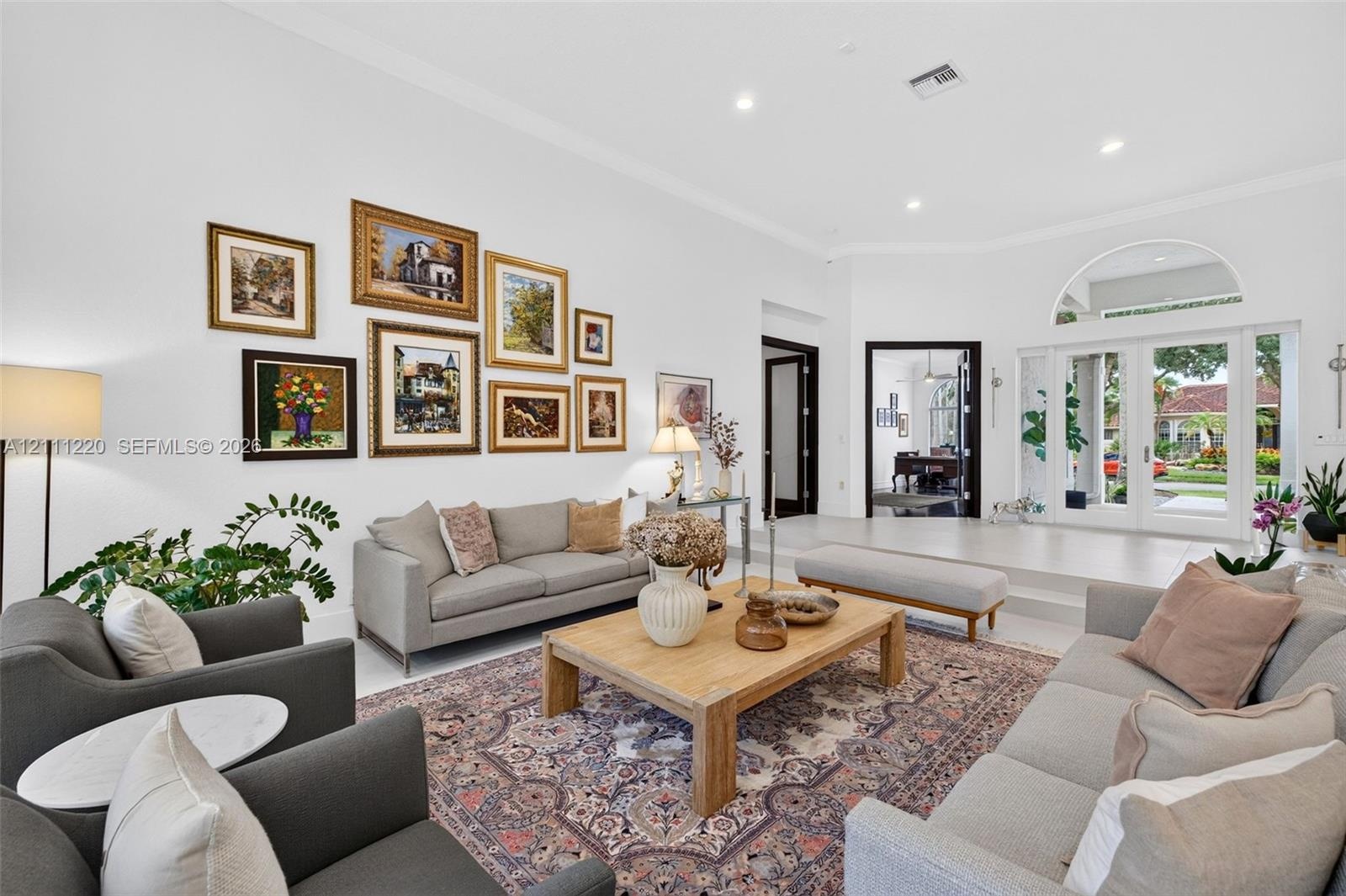 High ceilings featuring recessed lighting, expansive glass double doors with an arched transom, and light-toned hard-surface flooring