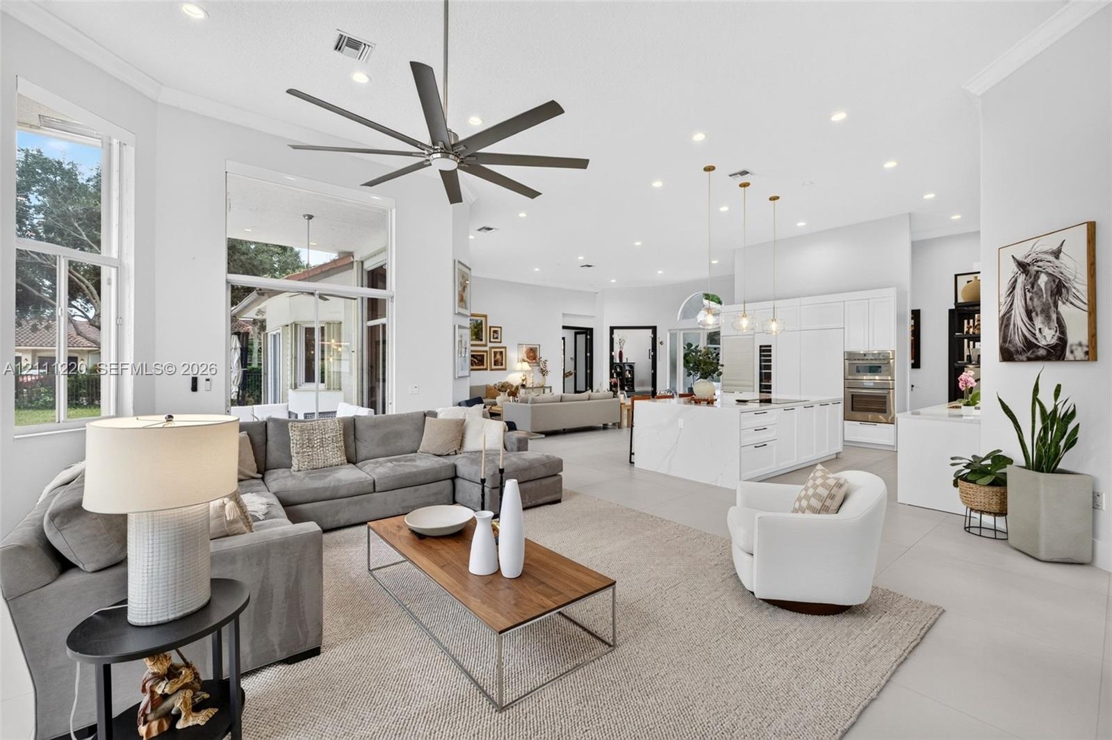 Open-concept living area featuring high ceilings, recessed lighting, large-format tile flooring, a chef's kitchen with a waterfall island, and a multi