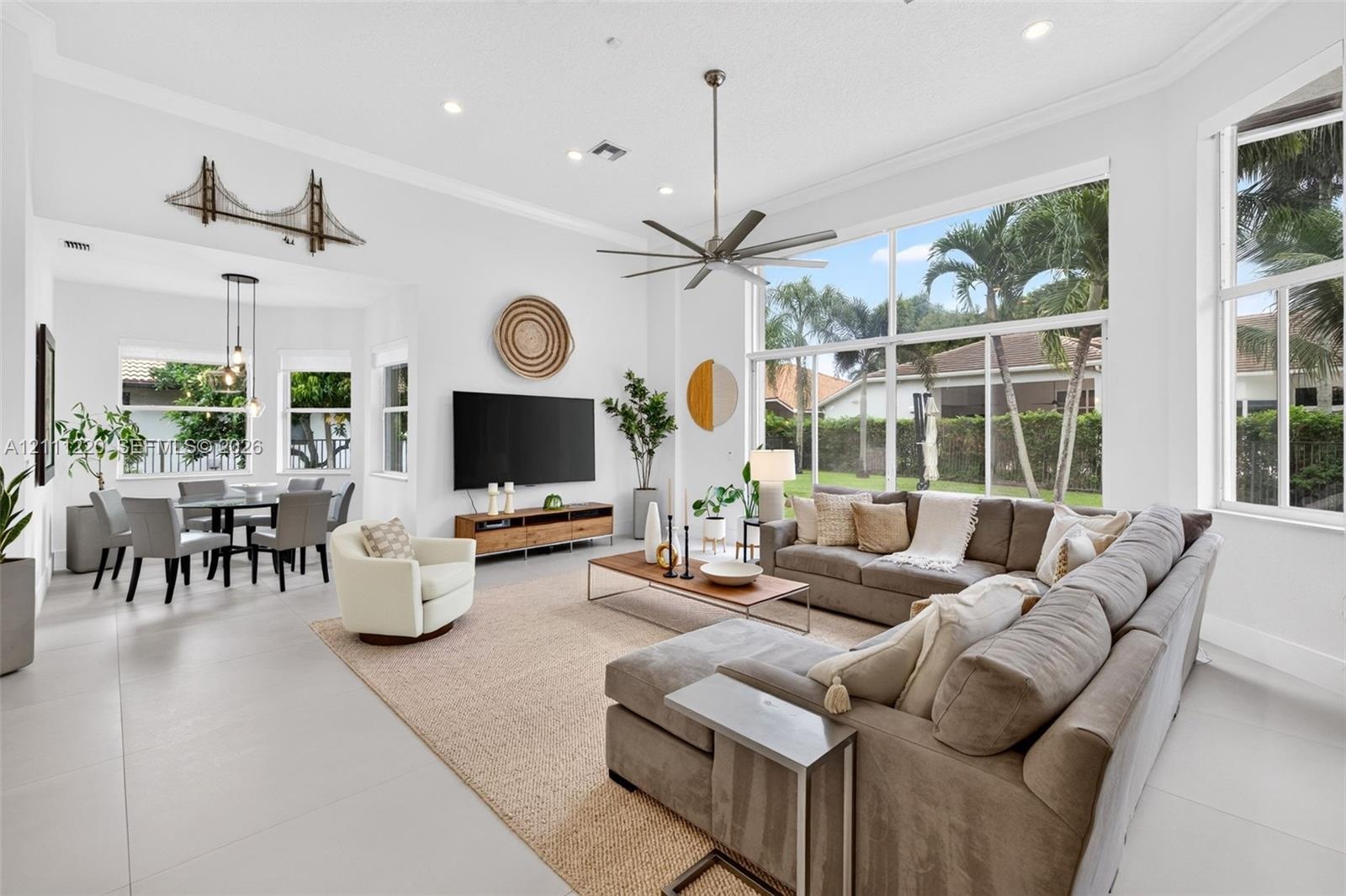 Expansive living space featuring soaring ceilings, floor-to-ceiling windows, uniform tile flooring, recessed lighting, and a multi-blade ceiling fan