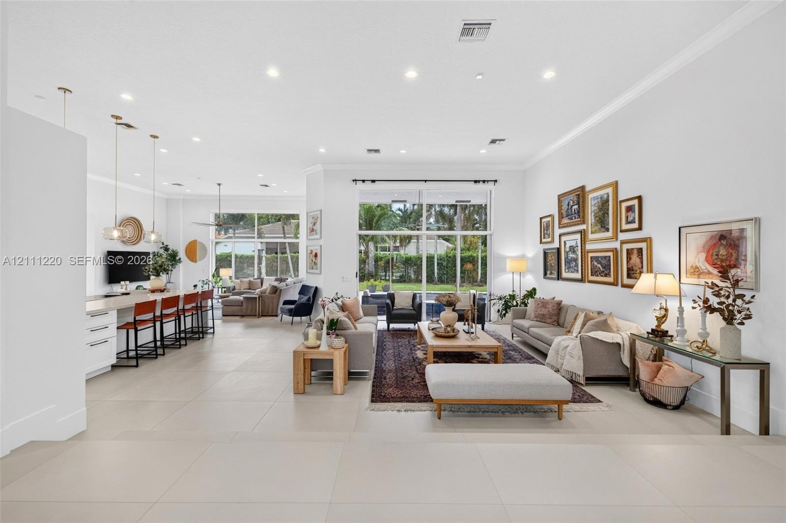 Open-concept living space featuring large-format tile flooring, recessed lighting, floor-to-ceiling glass windows, and a built-in kitchen island with 
